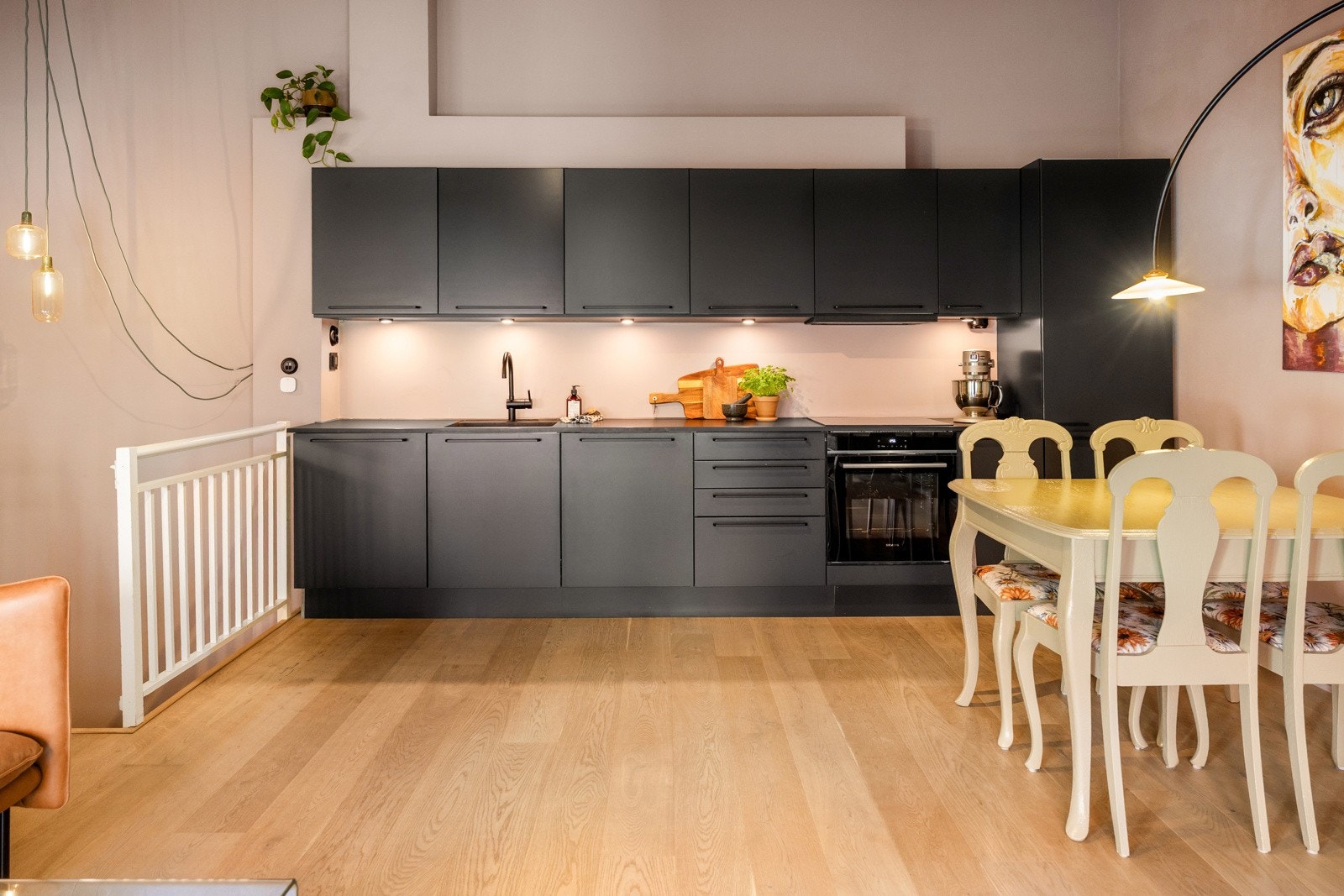 Pent kjøkken med slette fronter, sorte stålhåndtak og overskap med benkebelysning. Galleribilde