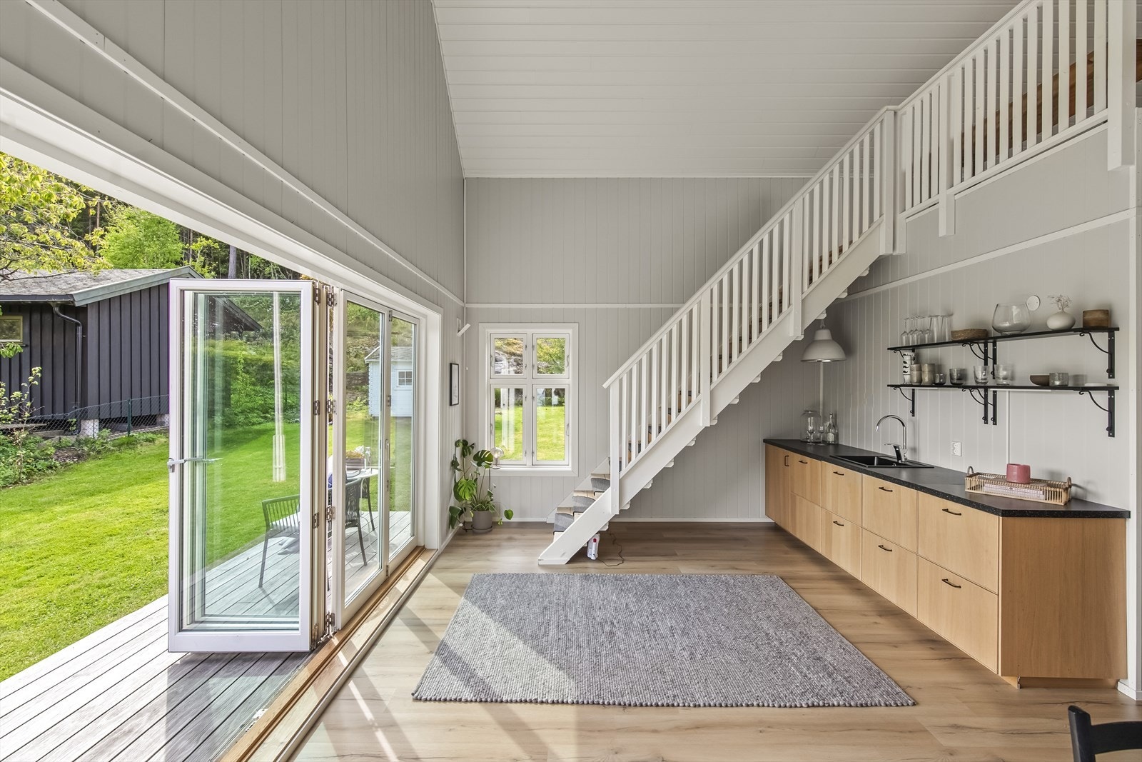 Oppholdsrommet er lyst og luftig, med høy himling og foldedører i glass som åpner ut til terrassen. Galleribilde