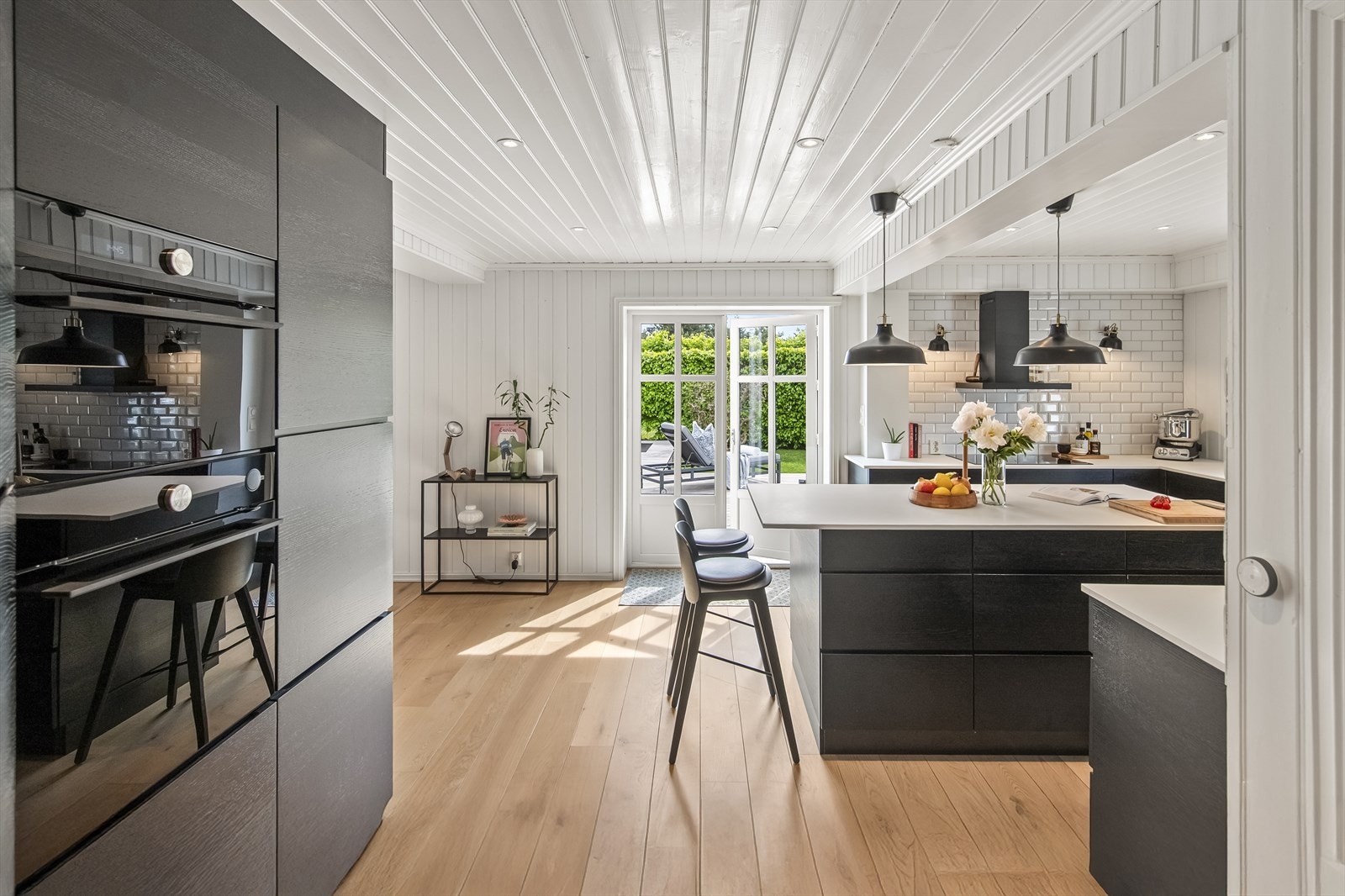 Innredningen er levert av Kvik, med stilrene, sorte fronter uten håndtak, og en benkeplate i laminat med nedfelt vask i matchende mørk tone. Galleribilde