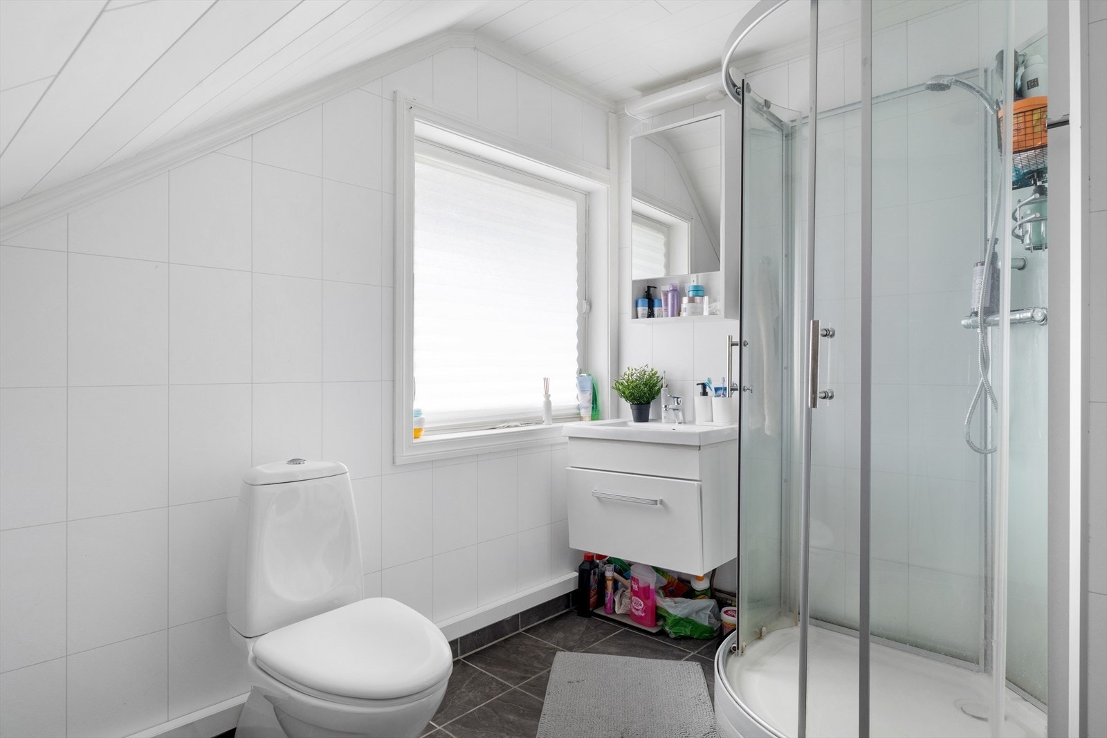 Bad i utleiedel i 2.etg. Fliser på gulv, baderomsplater på vegger. Wc, vask og dusjkabinett, samt varmekabler i gulv Galleribilde