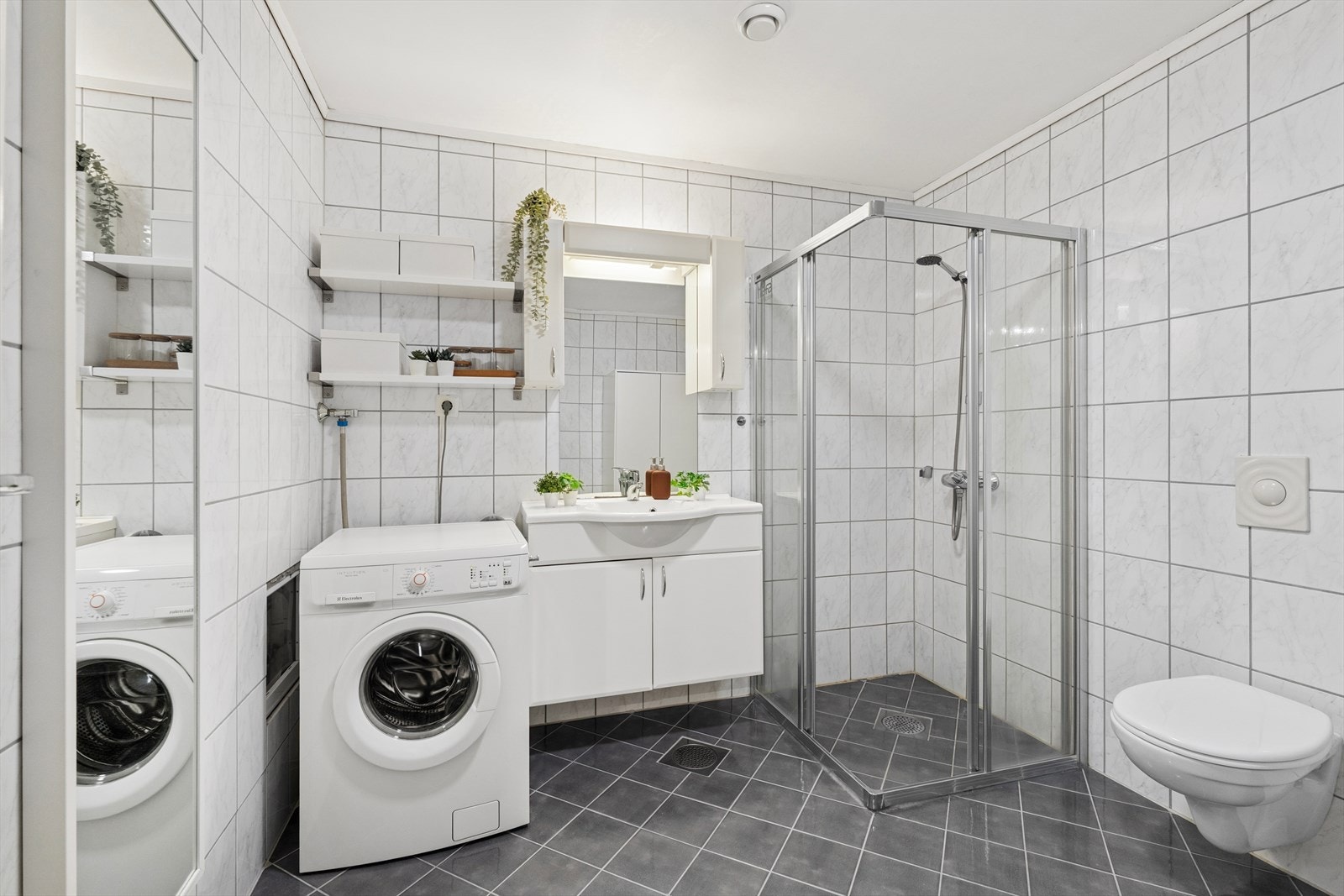 Badet har vegghengt toalett, dusjnisje, nedfelt servant og opplegg for vaskemasin Galleribilde