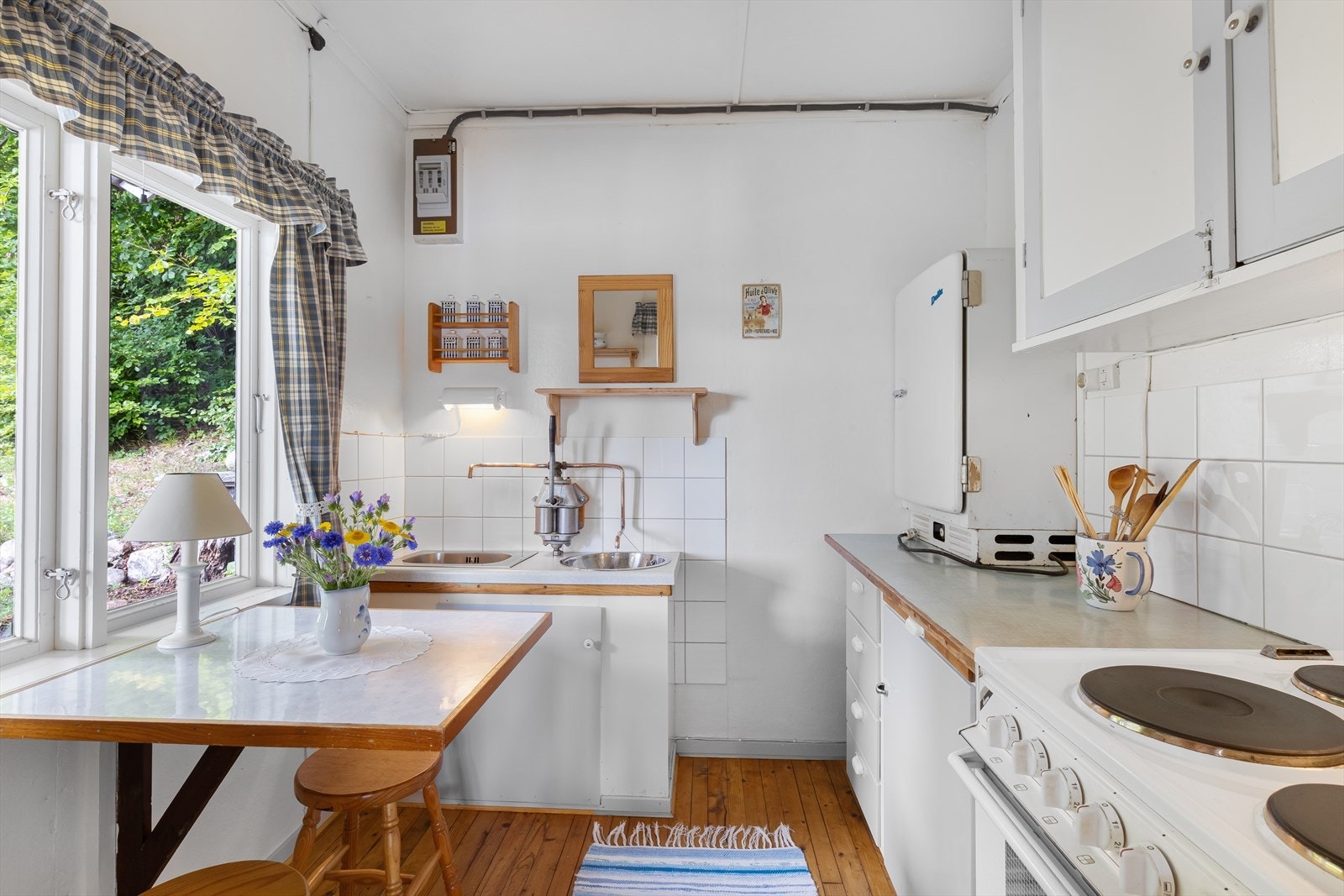Kjøkkenet ligger i eget rom og har spiseplass for to under vindu. Ved oppvaskbenken er det pumpe til brønnen. Galleribilde