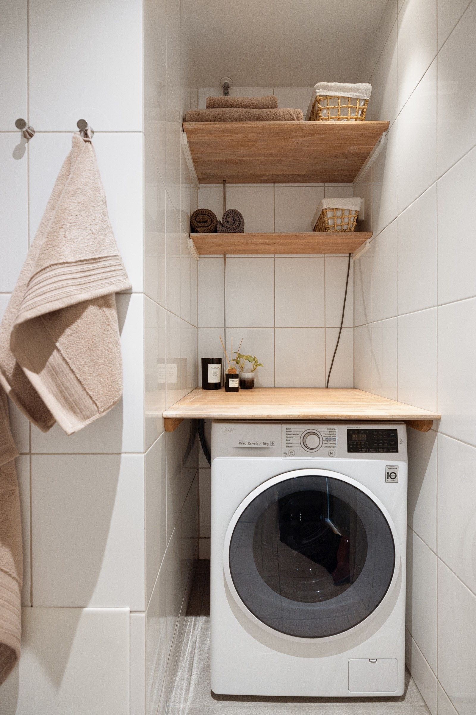 Praktisk nisje med plass og opplegg for vaskemaskin under benkeplate, samt vegghengte hyller over for oppbevaring. Galleribilde