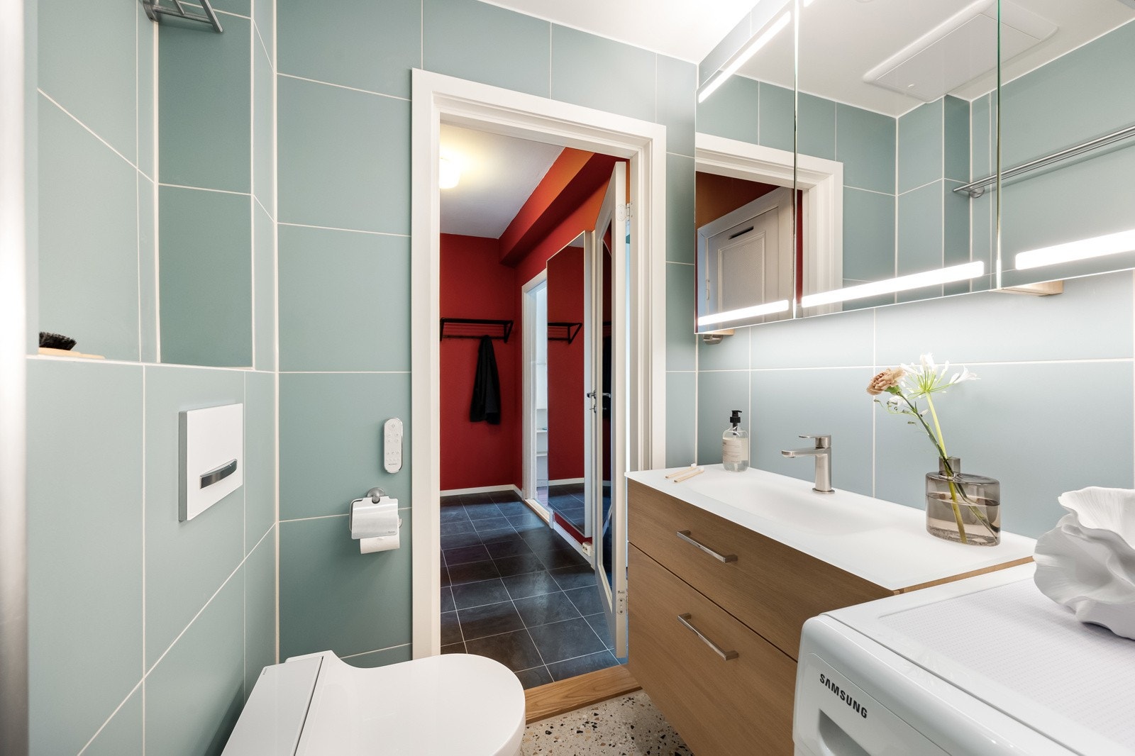 Flislagt baderom med varmekabler, dusjnisje, veggmontert servantskap og dusjtoalett samt opplegg for vaskemaskin Galleribilde