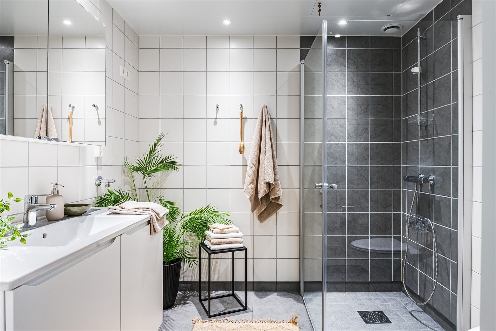 Det romslige og pene badet ligger med adkomst fra gang. Her er det fliser på vegger og gulv i et samstemt og pent preg. Badet har en romslig dusjhjørne med glassdører som kan skyves til siden og vegghengt wc. Gulvet har varmekabler og det er downlights. Galleribilde