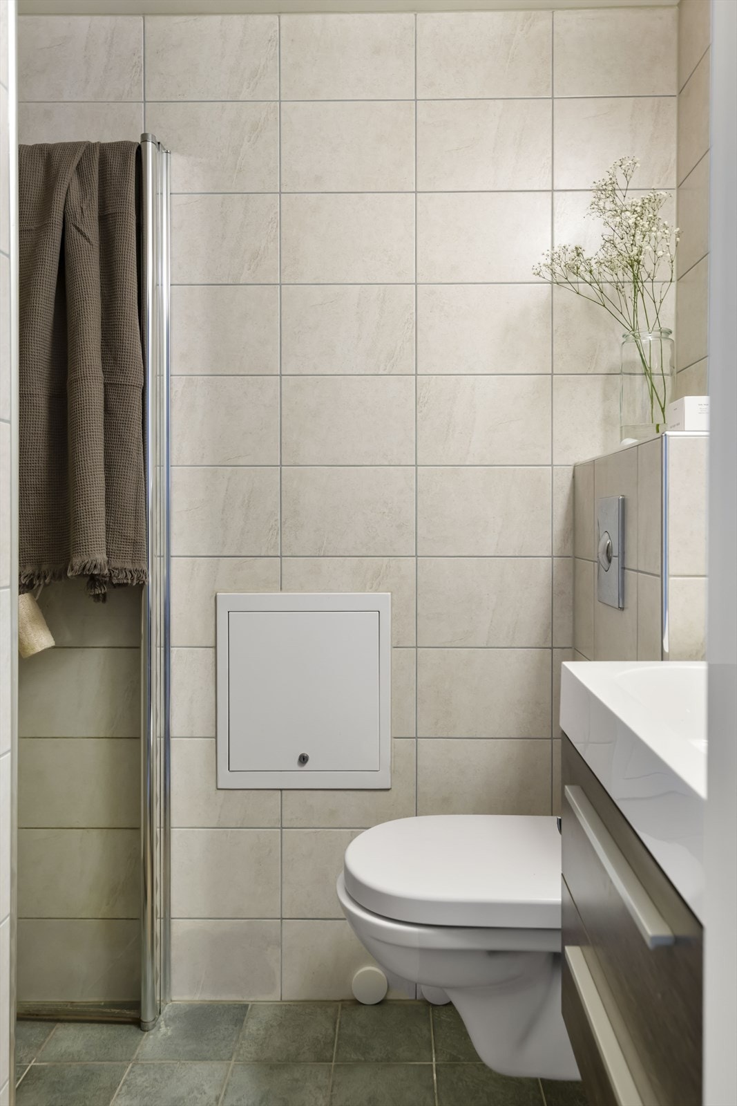 Badet har vegghengt toalett, dusjhjørne og servant med innredning Galleribilde