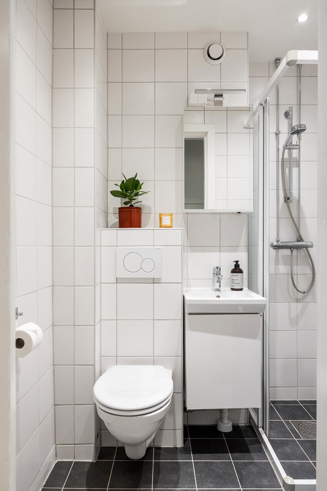 Badet har et stilrent uttrykk og er utstyrt med servantskap med glatte, fabrikklakkerte fronter, heldekkende servant og speilskap med integrert belysning. Dusjhjørnet har skyvedører i glass. Galleribilde