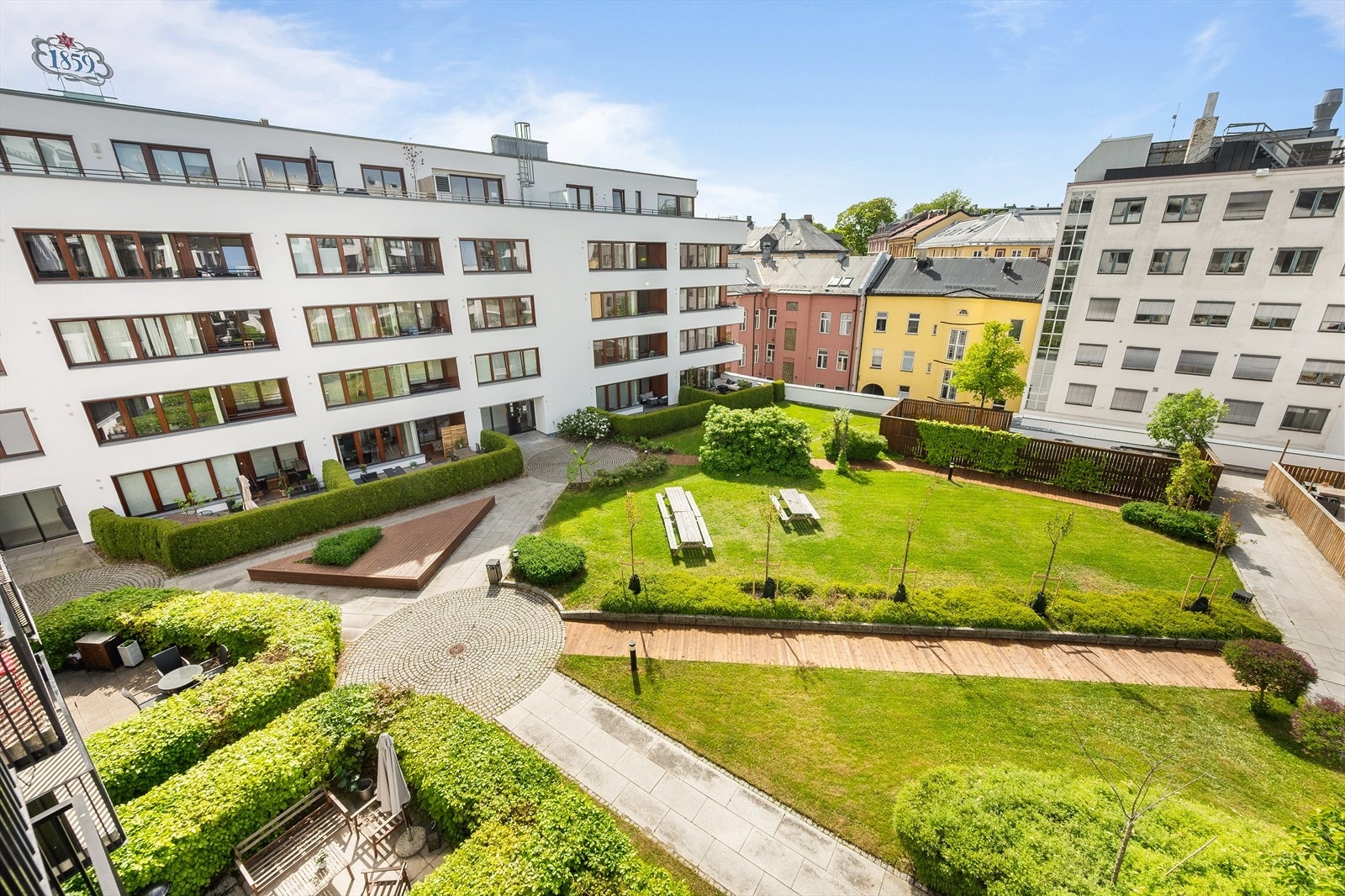 Frodig bakhage med sittegrupper, internveier og beplantning. Galleribilde