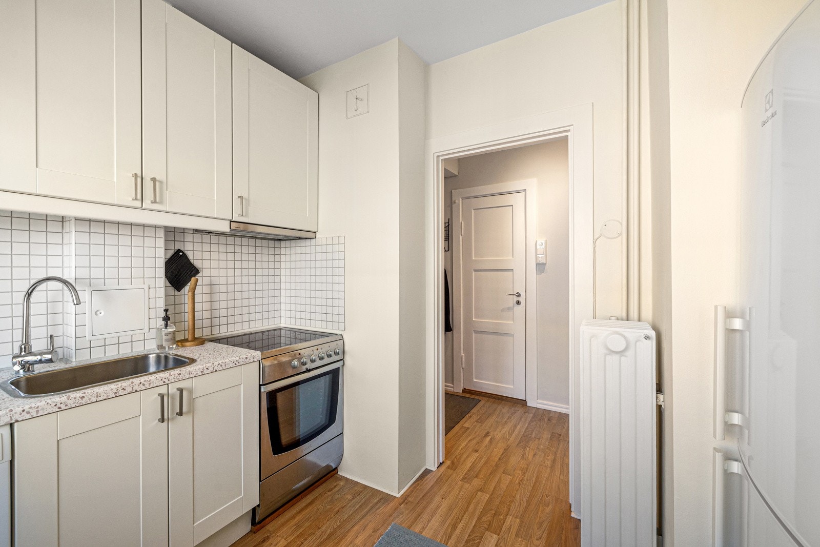 Kjøkkenet er utstyrt med fliser over benkeplaten, integrert koketopp, stekeovn, oppvaskmaskin og kjøleskap med fryser. Galleribilde