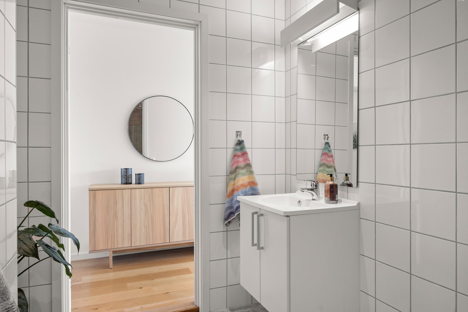 Badet har et stilrent uttrykk med servantskap med glatte, folierte fronter, heldekkende servant, speil og veggmontert belysning. Galleribilde