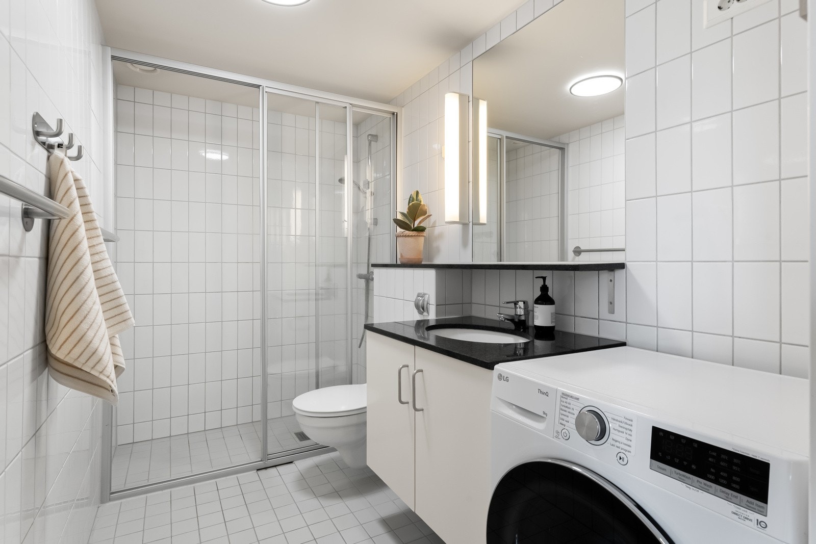 Flislagt bad med baderomsinnredning med speilskap. Galleribilde