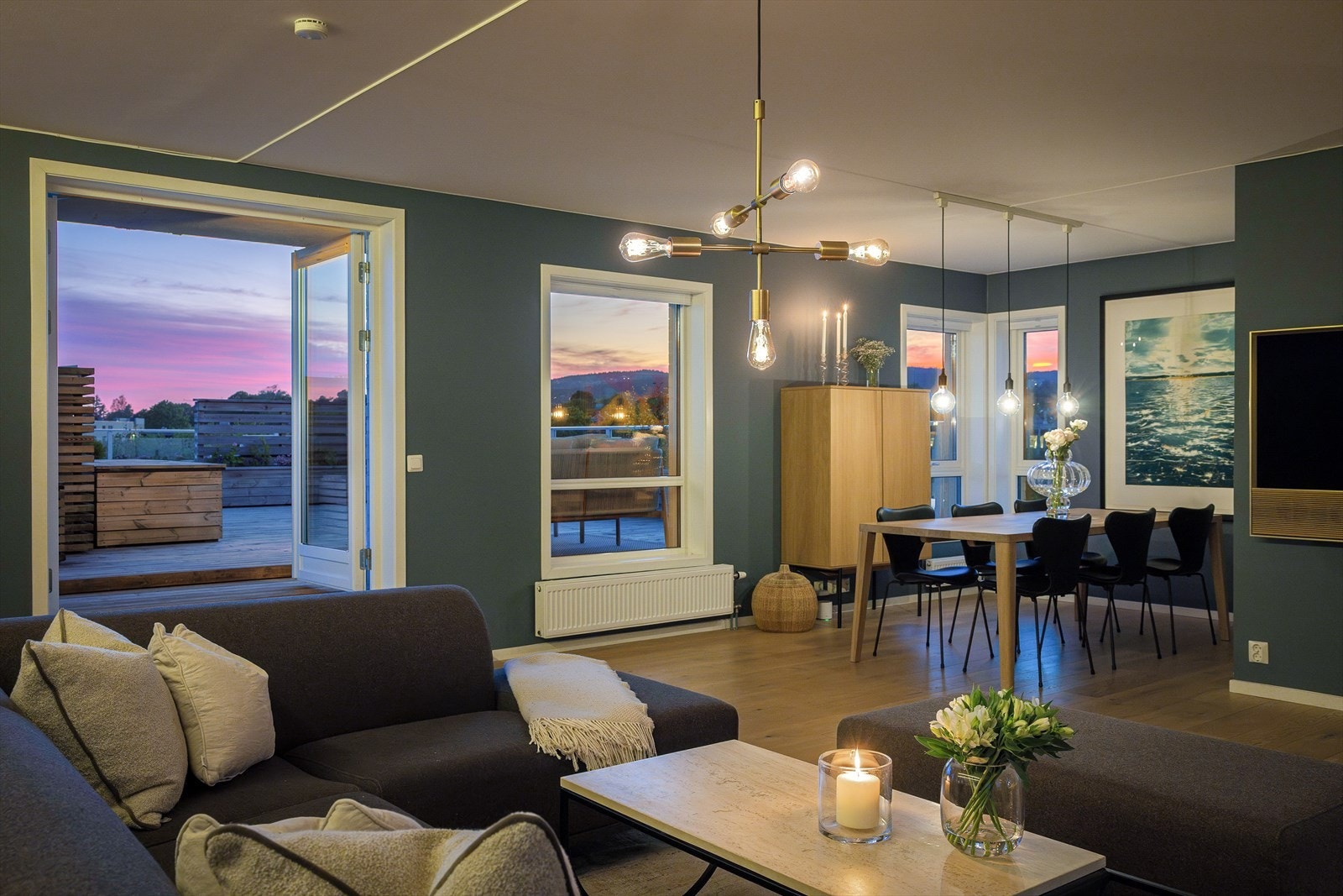 Stemningsfullt kveldslys fyller den åpne og moderne leiligheten, og skaper en varm atmosfære. Galleribilde