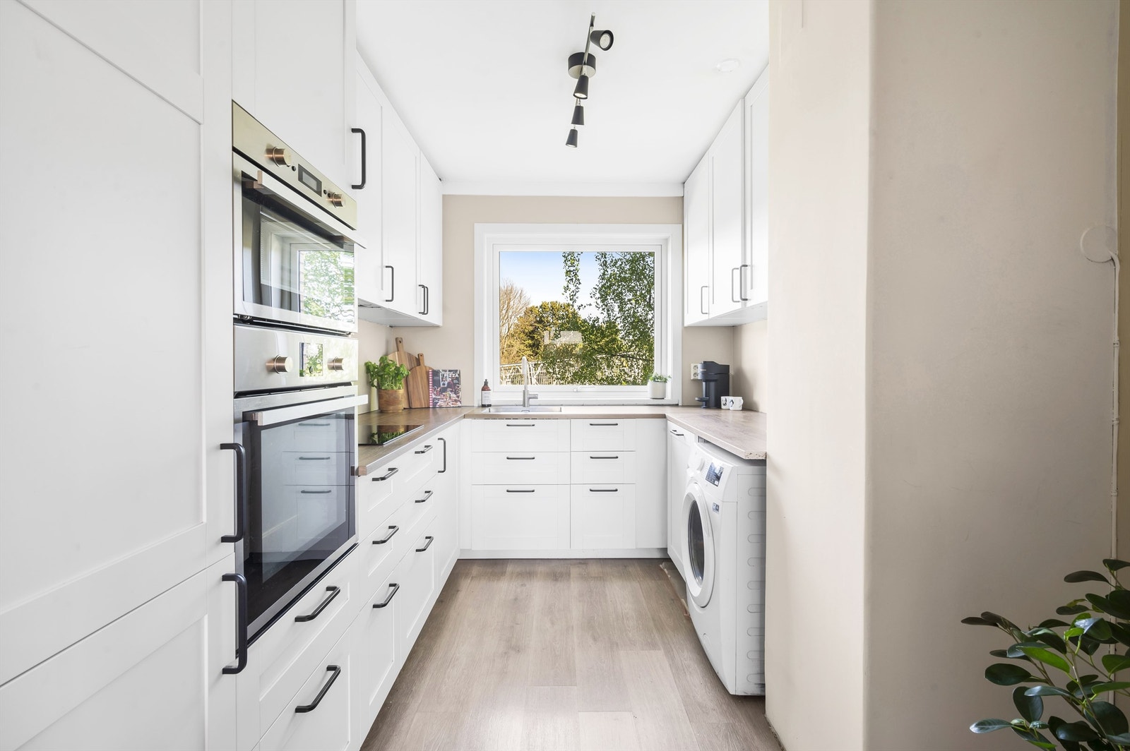 Kjøkkeninnredning med profilerte fronter og laminat benkeplate med nedfelt vaskekum. Av integrerte hvitevarer er det integrert platetopp, micro, stekeovn, oppvaskmaskin og kjøl/frys. Opplegg for vaskemaskin. Galleribilde