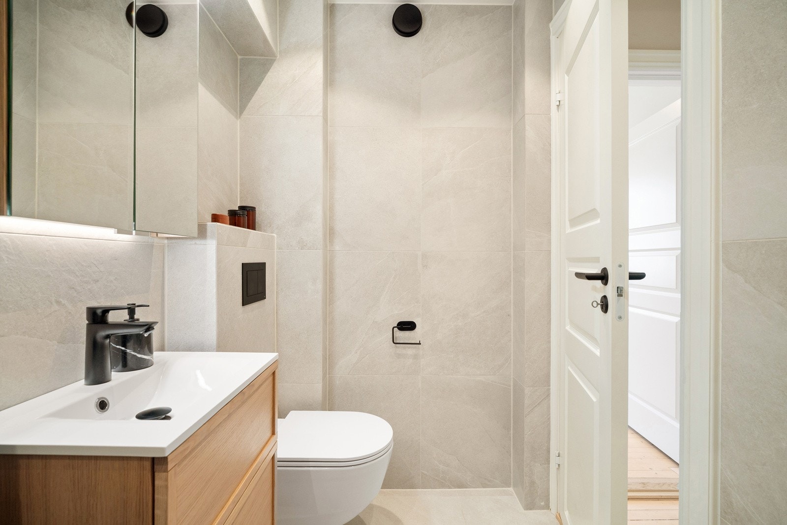 Pen baderomsinnredning med speilskap. Det er opplegg for vaskemaskin på badet. Galleribilde