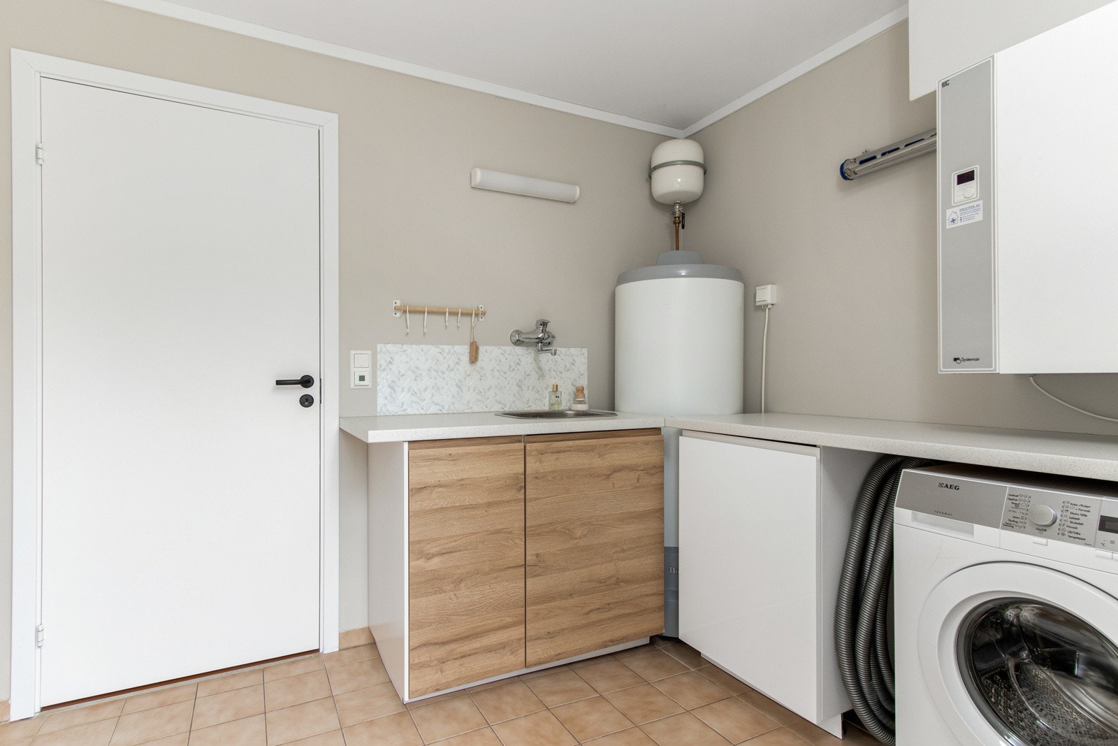 I første etasje ligger et romslig vaskerom med egen utgang til terrasse og hage Galleribilde