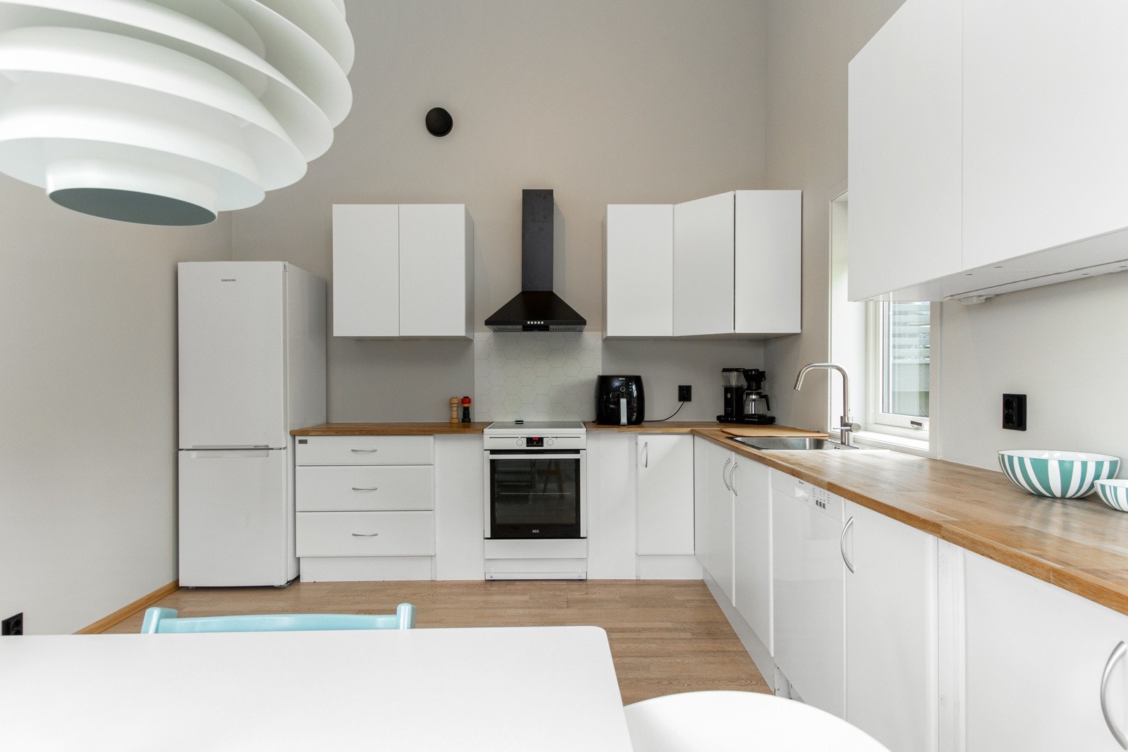 Kjøkkenet ligger i en luftig, åpen løsning med stuen og har tidløs innredning som byr på god skap- og benkeplass Galleribilde