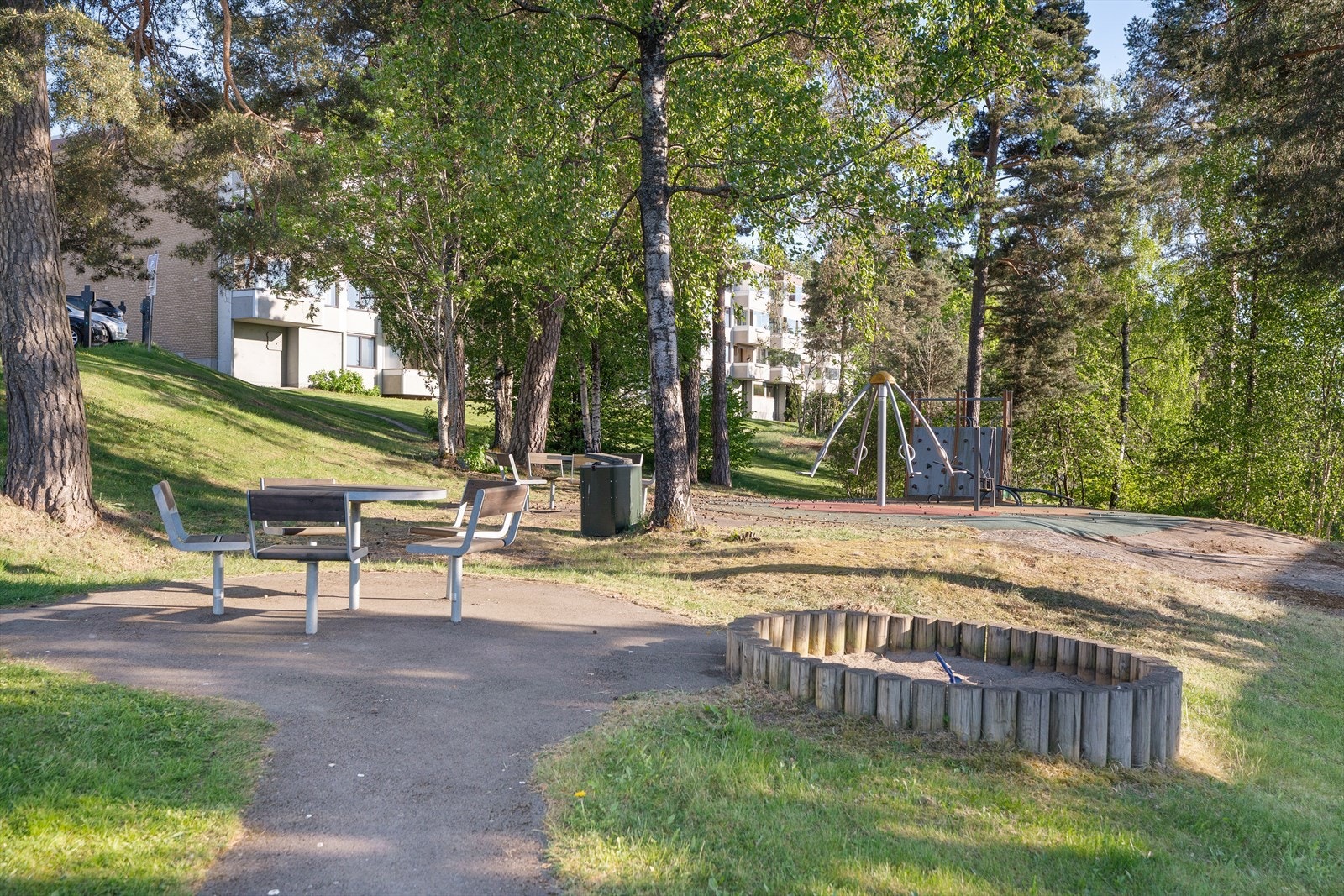 Et idyllisk og barnevennlig uteområde rett utenfor døren! Her finner du både lekeplass, sandkasse og hyggelige sittegrupper - perfekt for sosiale stunder og lek i trygge omgivelser. Galleribilde