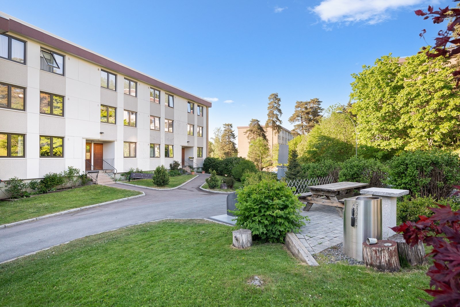 Innbydende inngangsparti omkranset av velstelte grøntområder. Til høyre i bildet finner du en sittegruppe med grill. Galleribilde