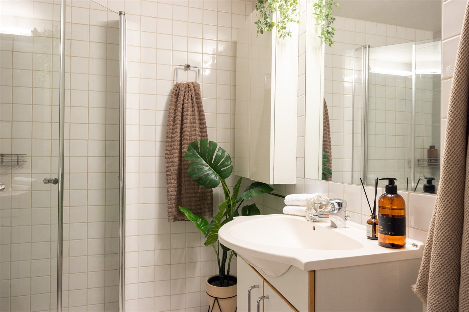 - Baderommet er innredet med vegghengt klosett, servant på innredning og dusjhjørne med svingbare glassdører - Galleribilde