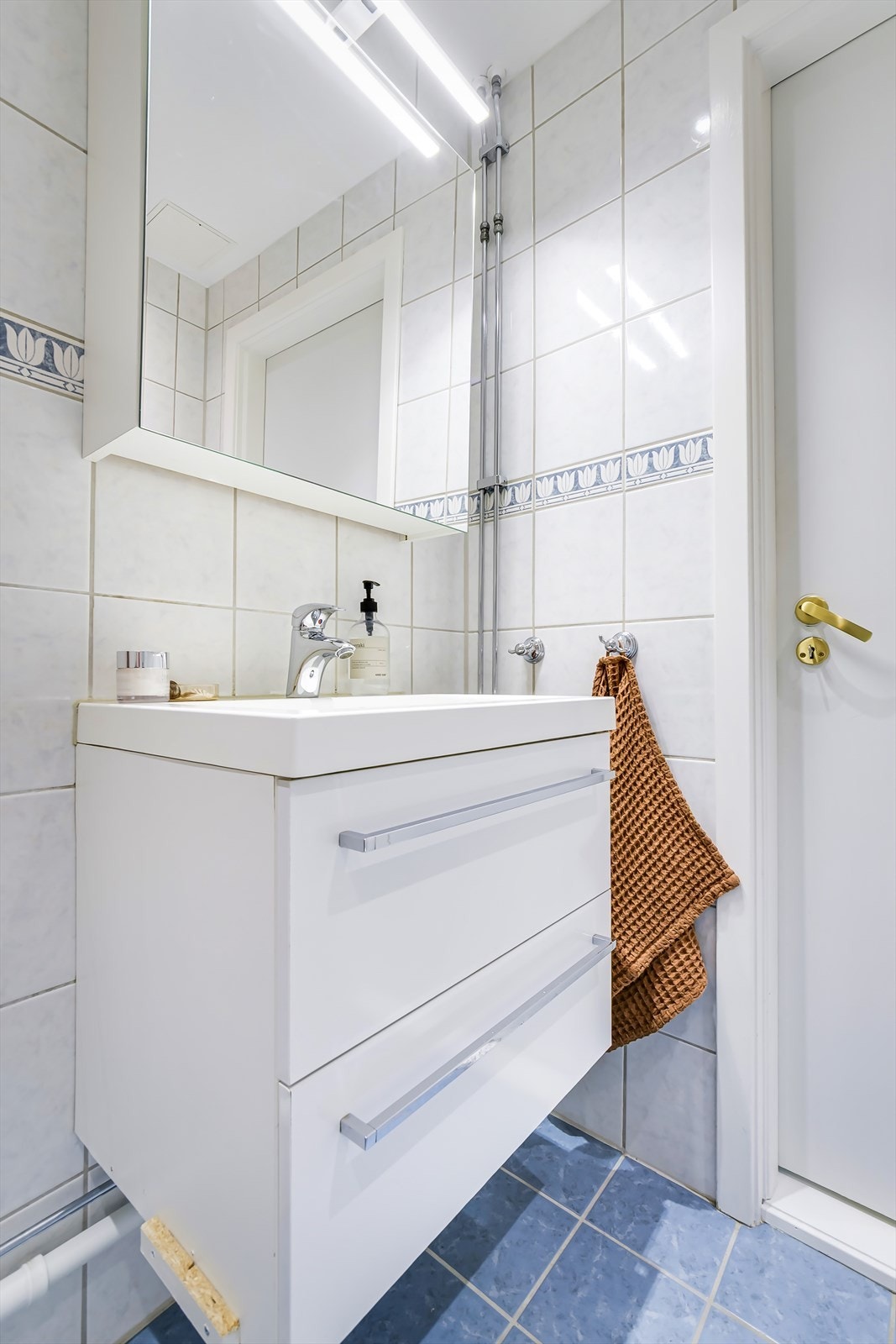 Badet er innredet med toalett, dusjplass med inn-utadslående dusjvegger, servant med ettgreps blandebatteri i innredning, speilskap og opplegg for vaskemaskin. Galleribilde