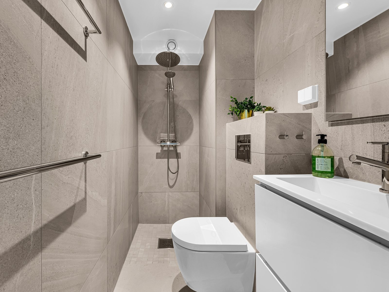 Gjestebad med direkte adkomst fra gangen, utstyrt med vegghengt WC og regnfallsdusj. Galleribilde