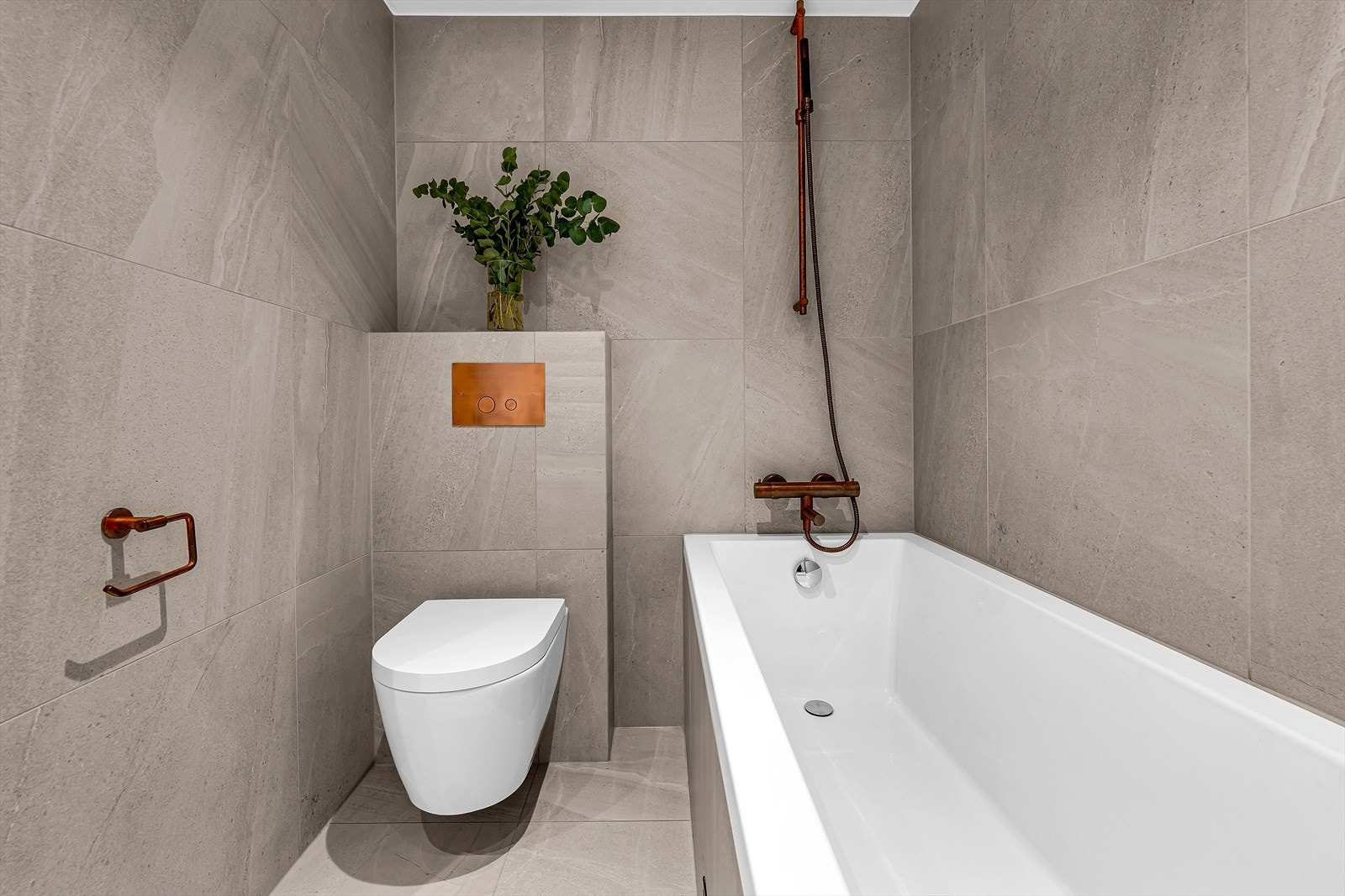 Badet er stilfullt utstyrt med vegghengt WC, elegant badekar og oppgraderte armaturer som gir et moderne preg. Galleribilde