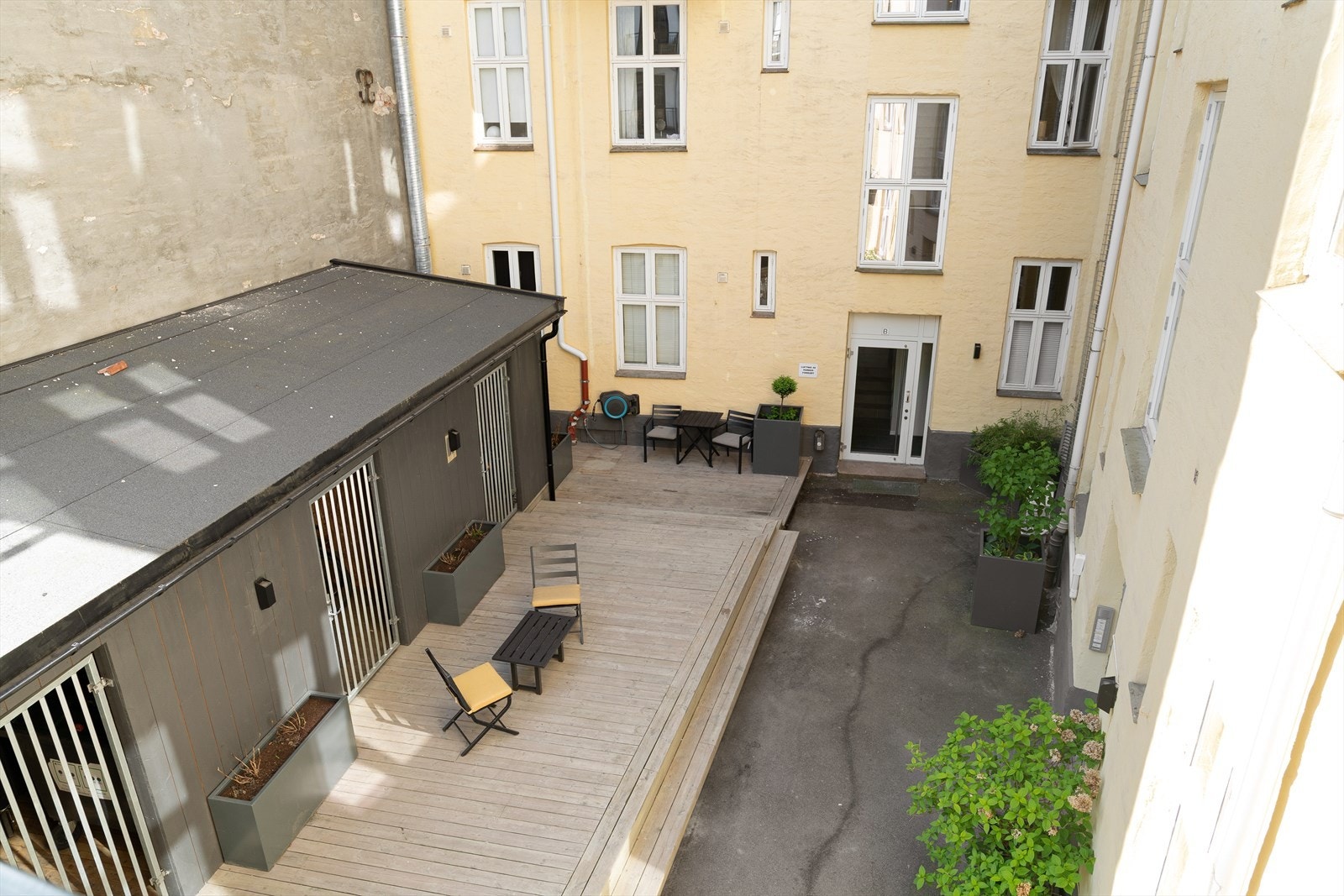 Bakgården er pent opparbeidet med terrasseplatting, sykkelparkering og krukker med frodig beplantning. Galleribilde