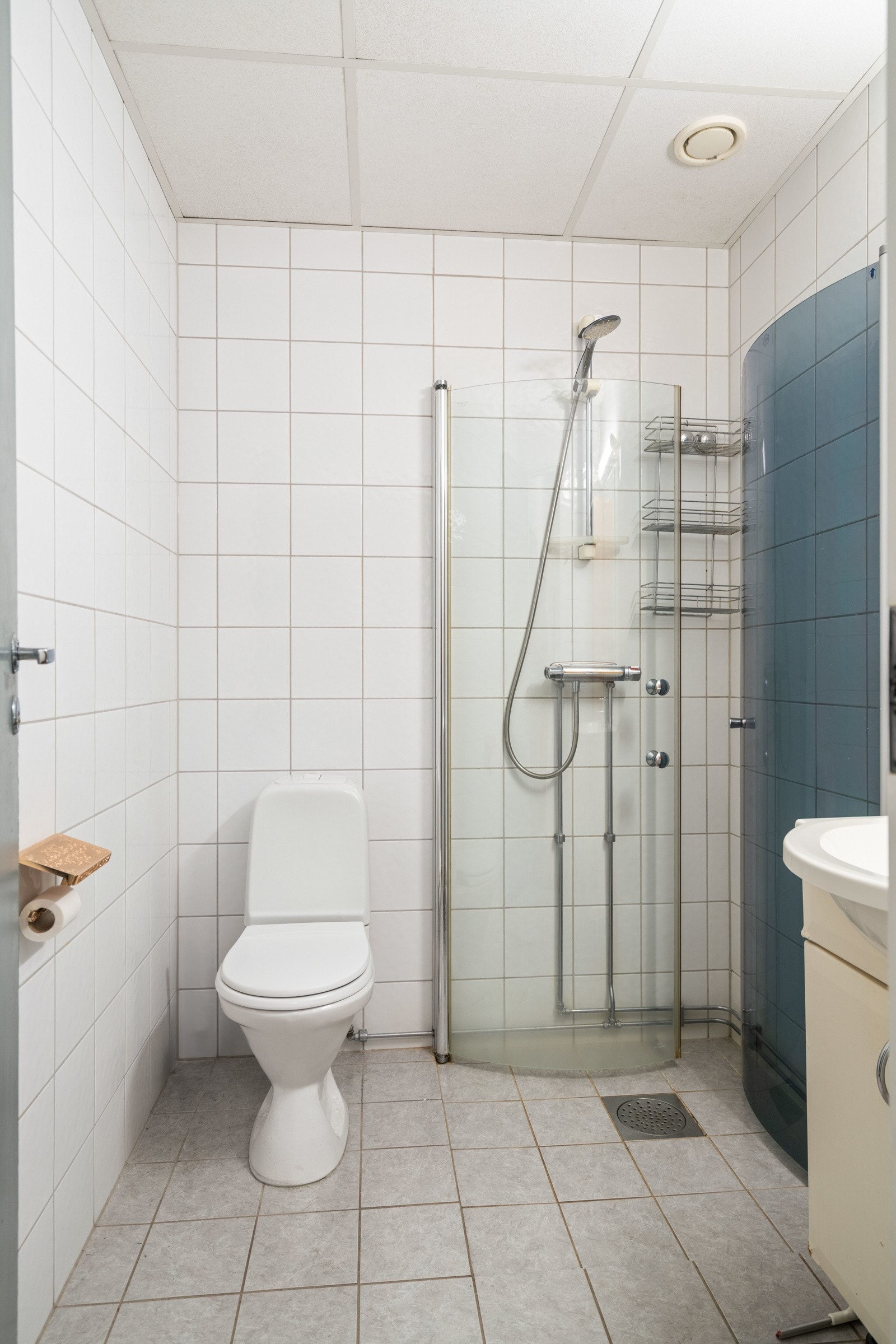 Baderom to med gulvstående toalett, dusjhjørne og opplegg for vaskemaskin. Flislagt gulv med varme. Galleribilde