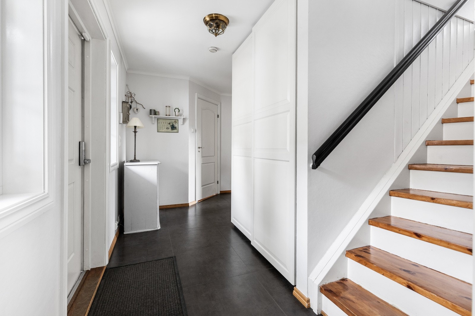 Romslig hall med montert skyvedørsgarderobe, som gjør det enkelt å rydde sko og jakker ut av syne. Gangen leder videre til badet, vaskerom, kjøkken og stue Galleribilde