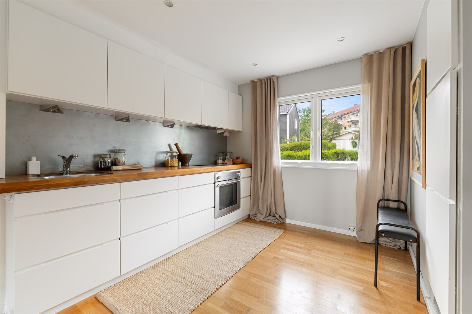 Innredning med hvite, slette fronter og benkeplate i tre og underlimt oppvaskkum med ett-greps armatur Galleribilde