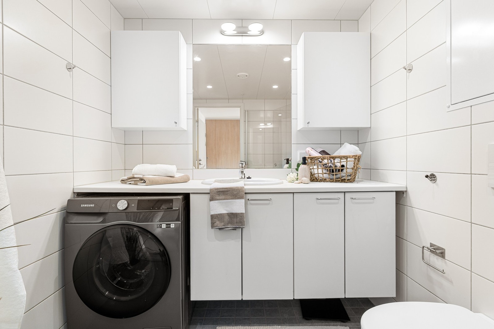 Badet er innredet med servant på underskap, overskap og speil. Servantplaten strekker seg fra vegg til vegg, og sørger for en praktisk og funksjonell løsning i hverdagen. Galleribilde