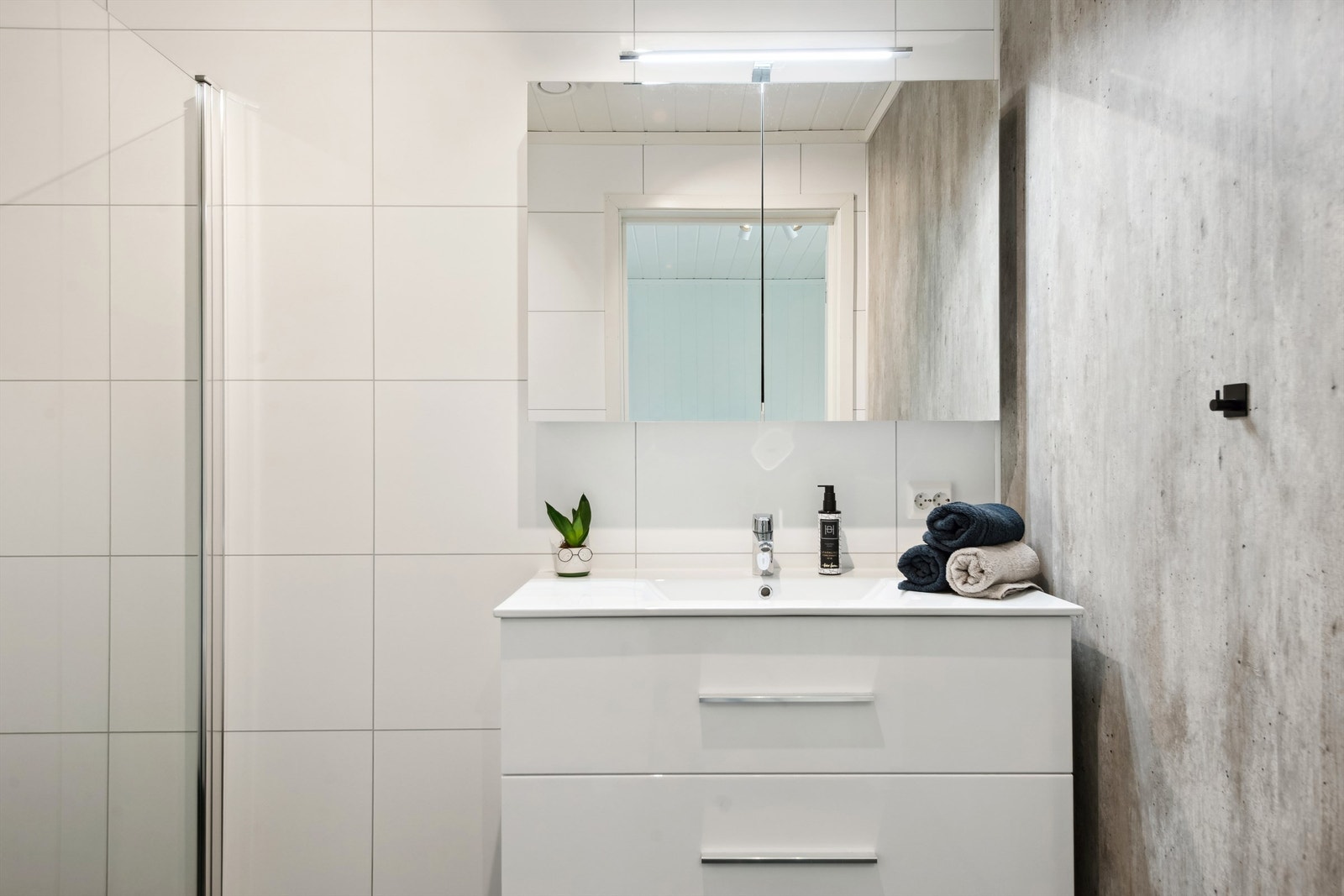 Badet har heldekkende servant og speilskap Galleribilde