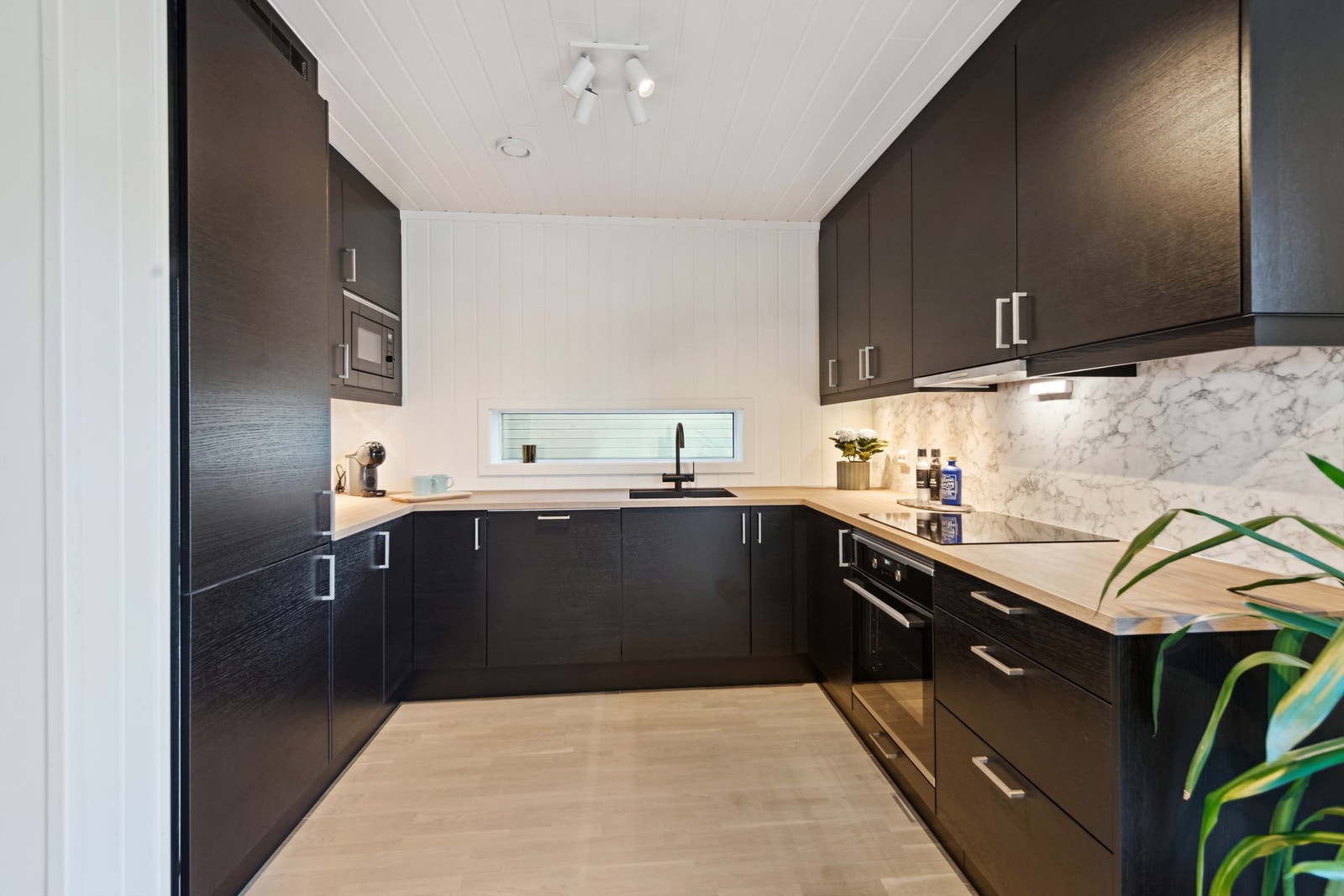 Kjøkkenet er stilrent innredet med mørke fronter Galleribilde