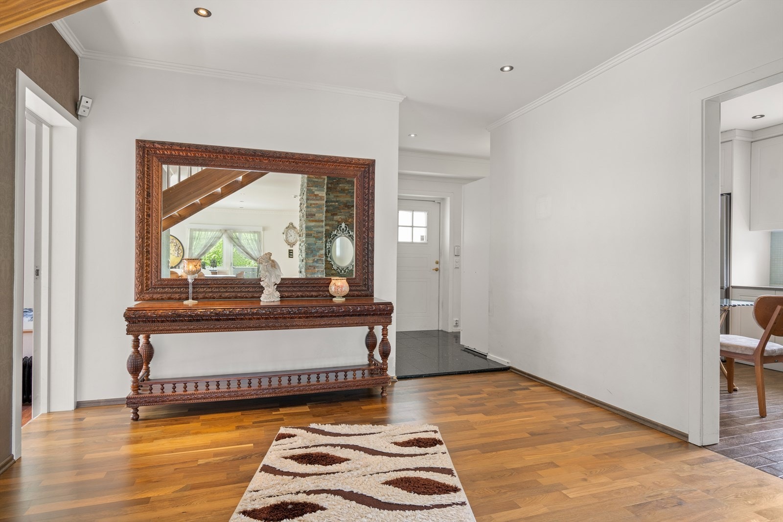 Lys og innbydende entre med delikate storformatfliser på gulv og lysmalte slette veggflater. Downlights i himling. Galleribilde