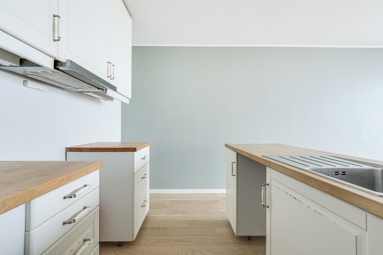 Hvit, stilren kjøkkeninnredning med rikelig skap- og benkeplass Galleribilde