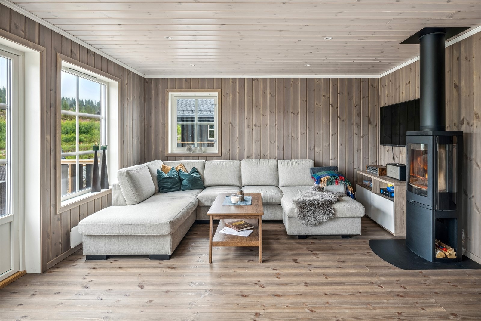 I dag er stuen innredet med romslig sofagruppe nær den moderne peisvedovnen. En fin plass for familien og samles til tv-titting eller spillkvelder. Galleribilde