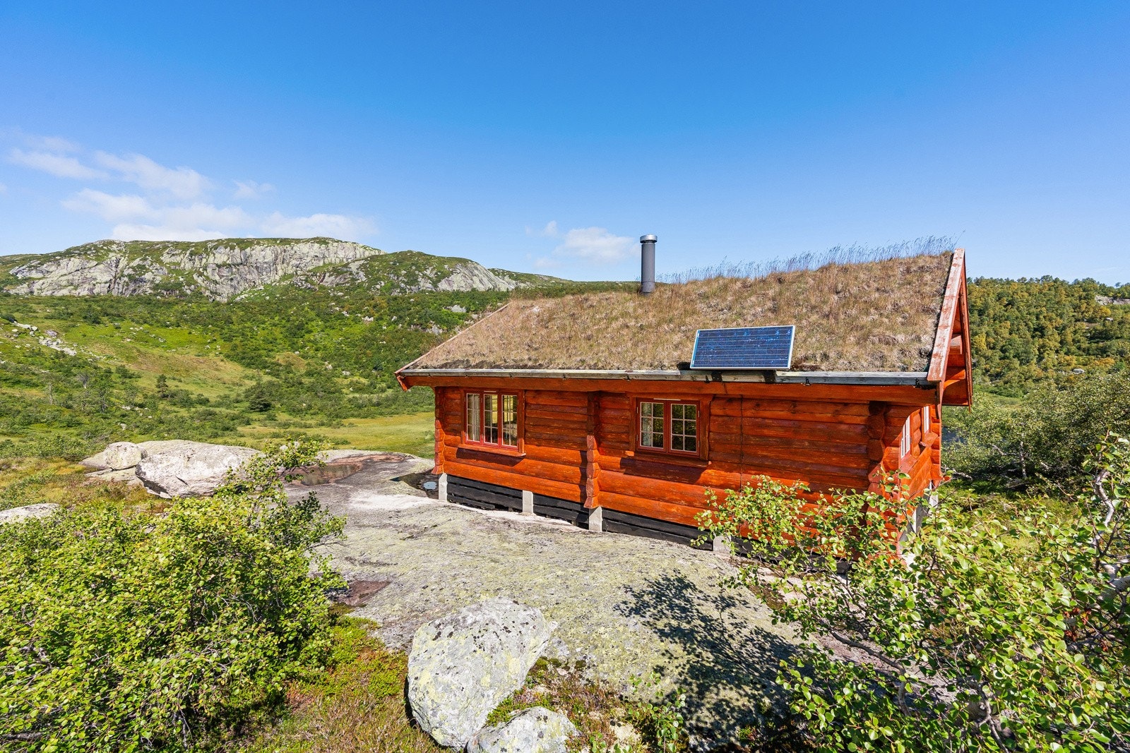 En lettstelt naturtomt med svaberg som omkranser hytta - pilarer på fjellgrunn. Galleribilde