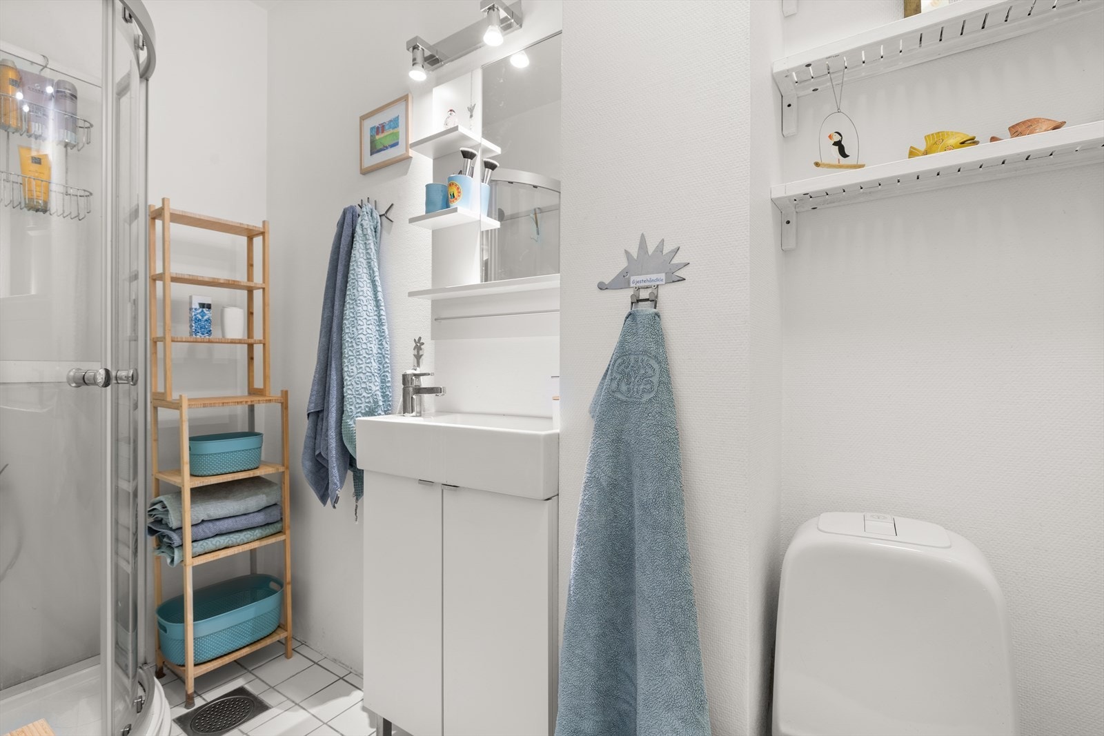 Badet er utstyrt med et praktisk dusjkabinett, gulvstående toalett og servant med servantskap. Galleribilde