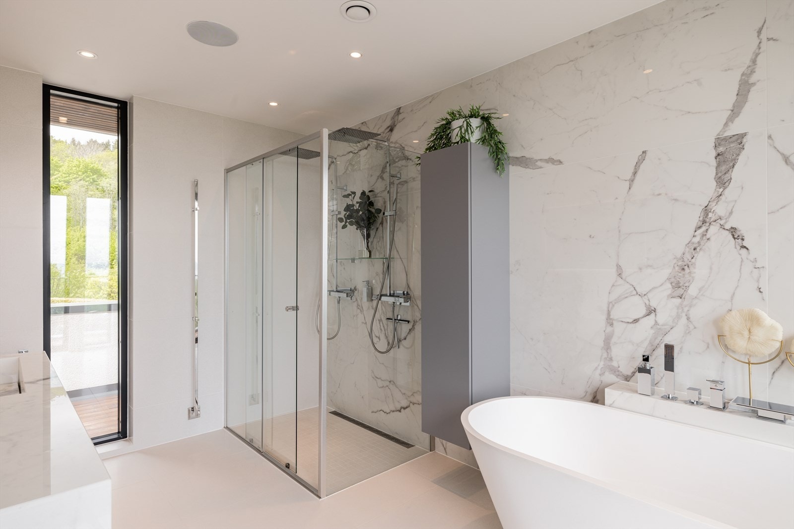 Spafølelsen blir komplett med et lekkert designbadekar fra Deco nude silkstone med fossefallskran, samt en stor dusjnisje med dobbel regnfallsdusj, hånddusj og glassvegger. Galleribilde