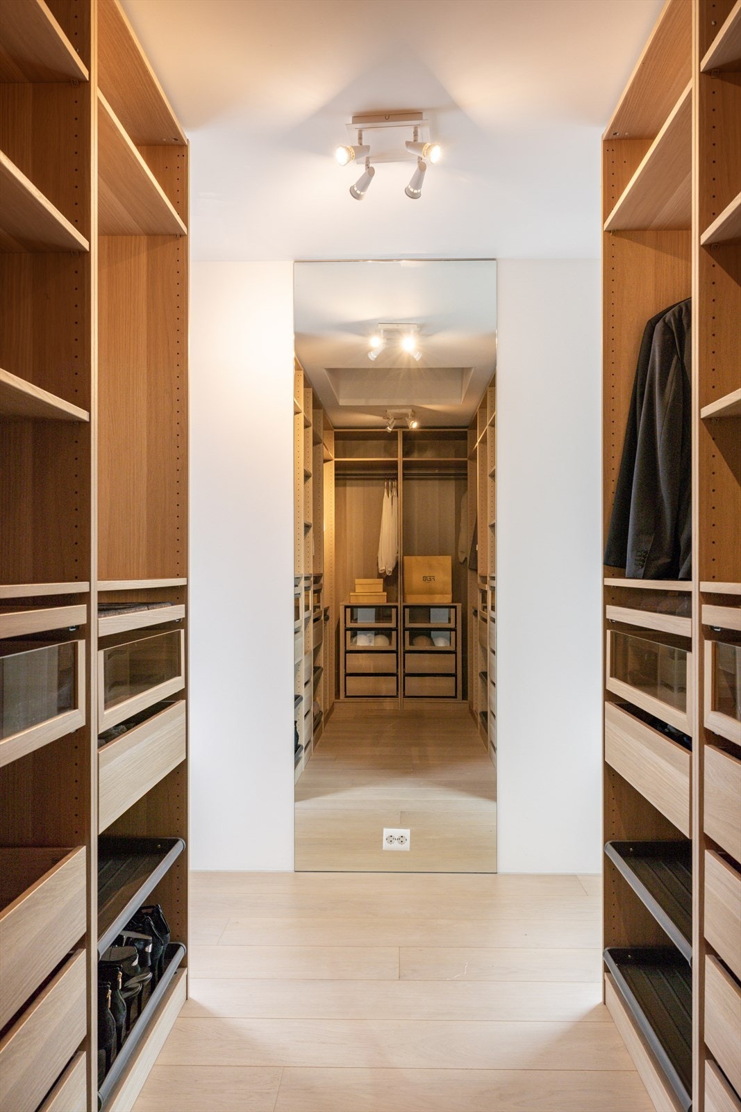 Omkledningsrommet er innredet med åpne garderobeskap i eikedesign med hyller, skuffer, heng og skohyller. Galleribilde