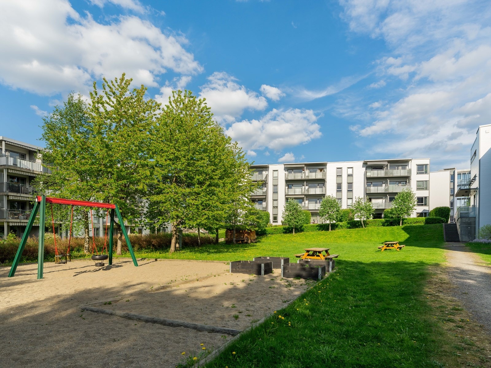 Pent opparbeidet felles tomt med plen, trær, diverse beplantning, lekeplass, sittebenker, asfalterte internveier og gjesteparkering. Galleribilde