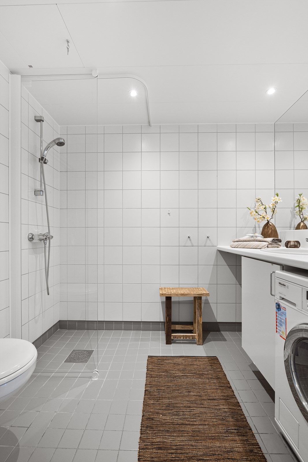 Innredningen består av servant med skapinnredning, innfelt speil over servant, vegghengt toalett og dusjhjørne med glassvegg. Galleribilde