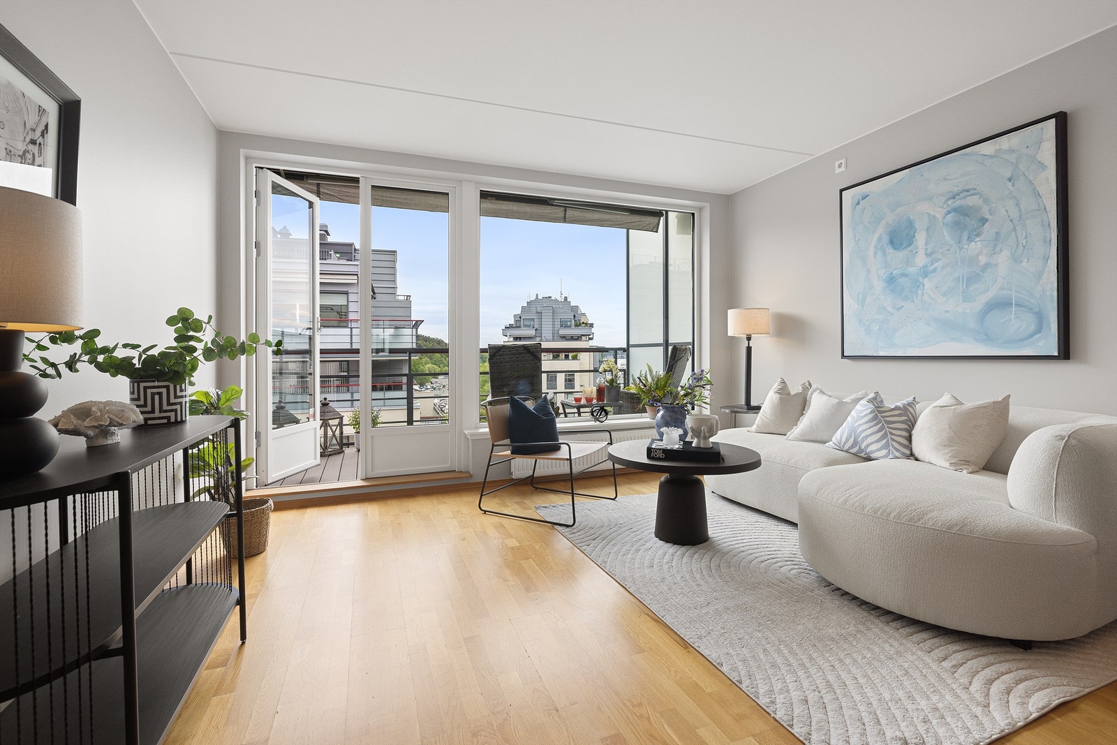 Lys og romslig stue med store vindusflater som slipper inn rikelig med lys og skaper en luftig atmosfære. Overflatene er holdt i lyse og tidsriktige fargevalg som harmonerer fint med resten av leiligheten. Galleribilde