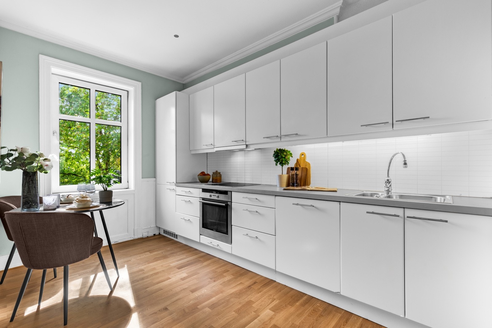 Separat kjøkken med innredningen med slette fronter i hvit-utførelse og benkeplate av malt heltre. Galleribilde