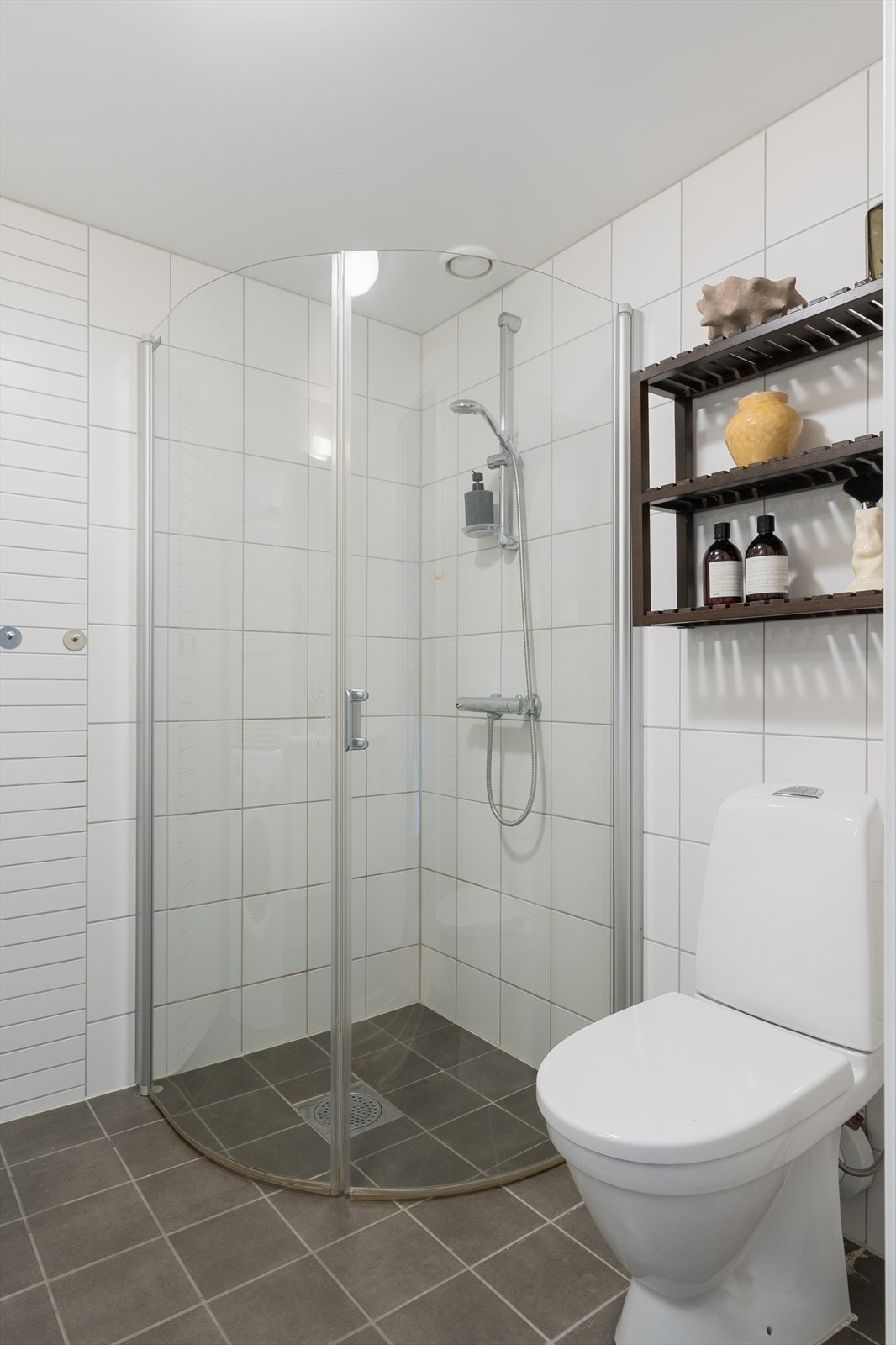 Badet er fra byggeår og er innredet med dusj, veggmontert servantskap og gulvstående klosett. Det er opplegg for vaskemaskin. Galleribilde