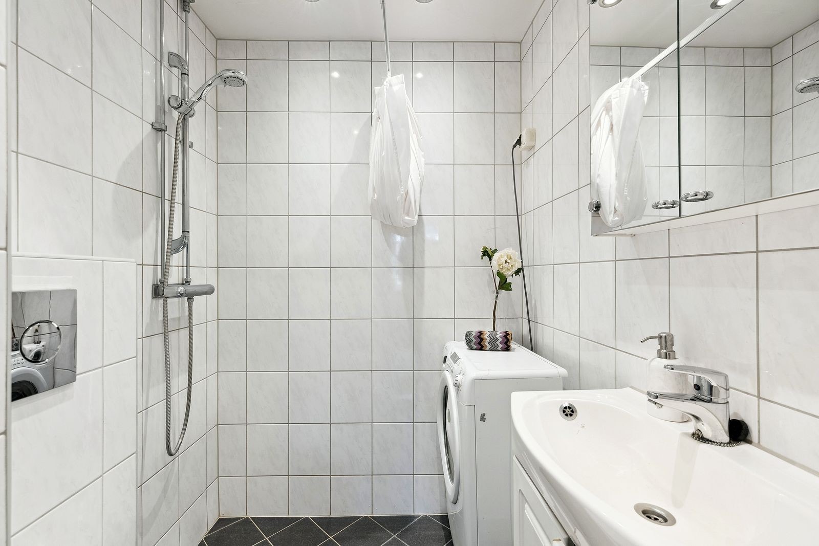 Badet er innredet med dusjhjørne, servant med underskap, speilskap over vask, vaskemaskin og wc. Galleribilde