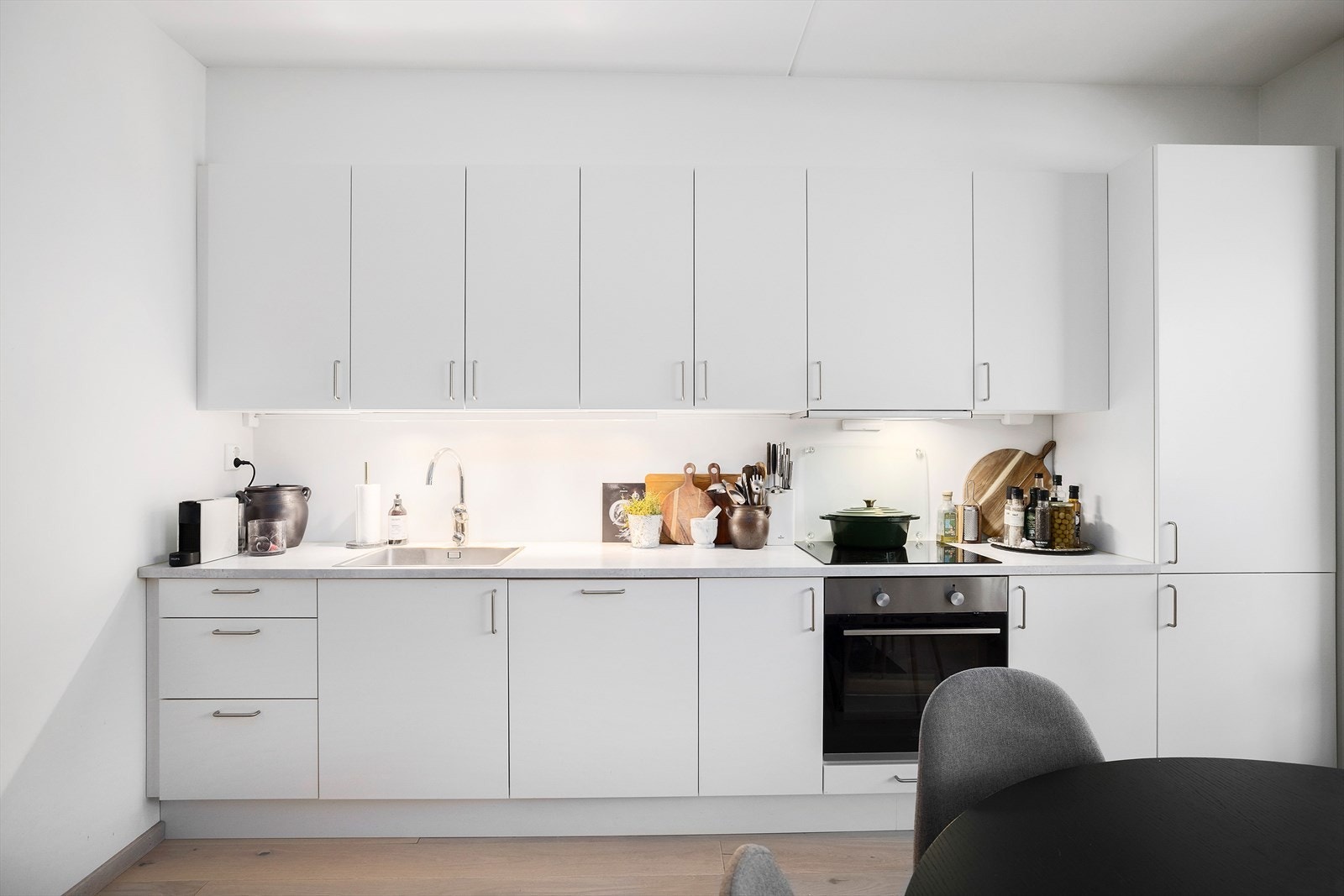 Kjøkkeninnredningen har hvite, slette fronter og laminert benkeplate Galleribilde