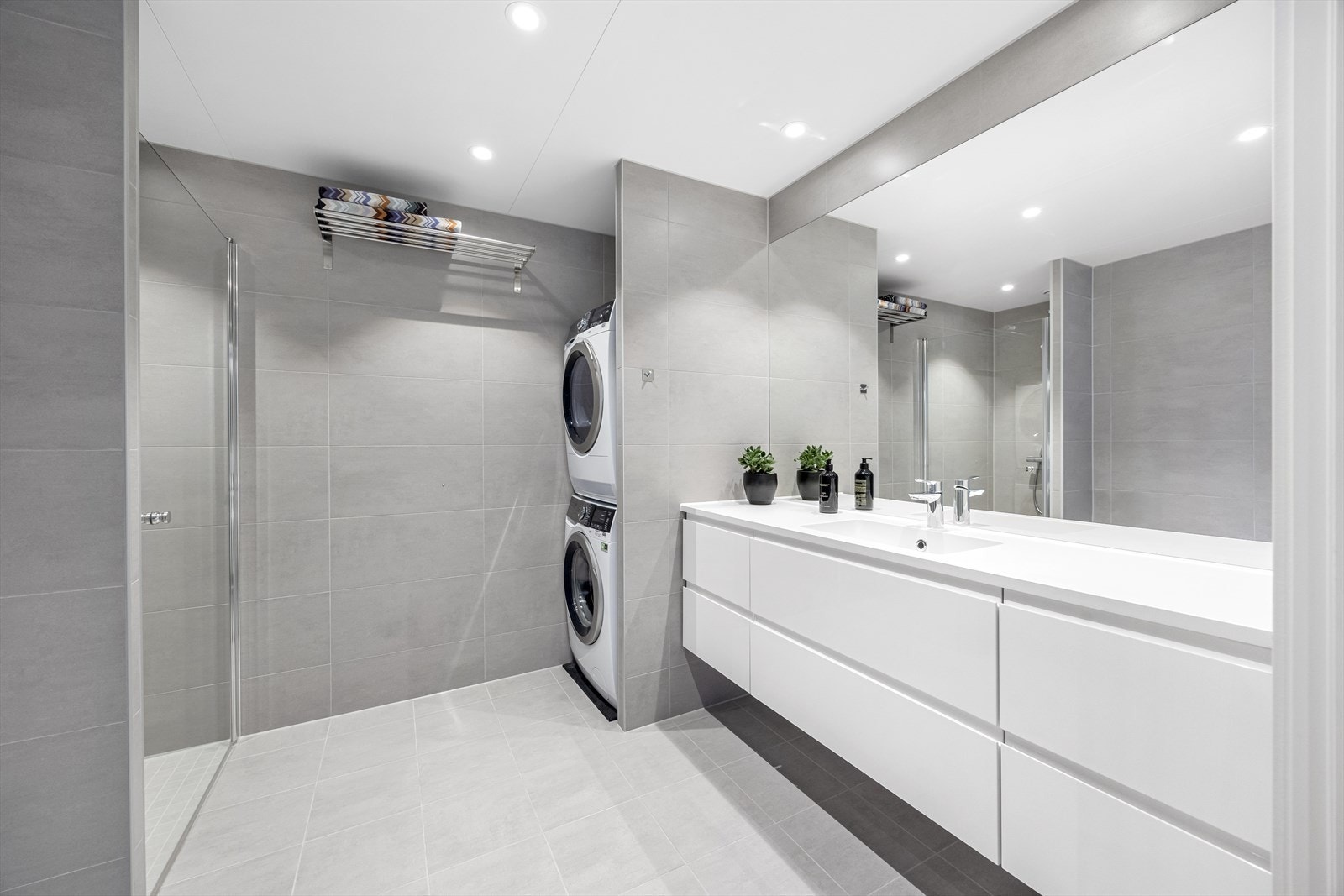 Badet er fliselagt til tak, har dusjnisje, bred servantinnredning og skjermet nisje for vaskemaskin og tørketrommel. Galleribilde