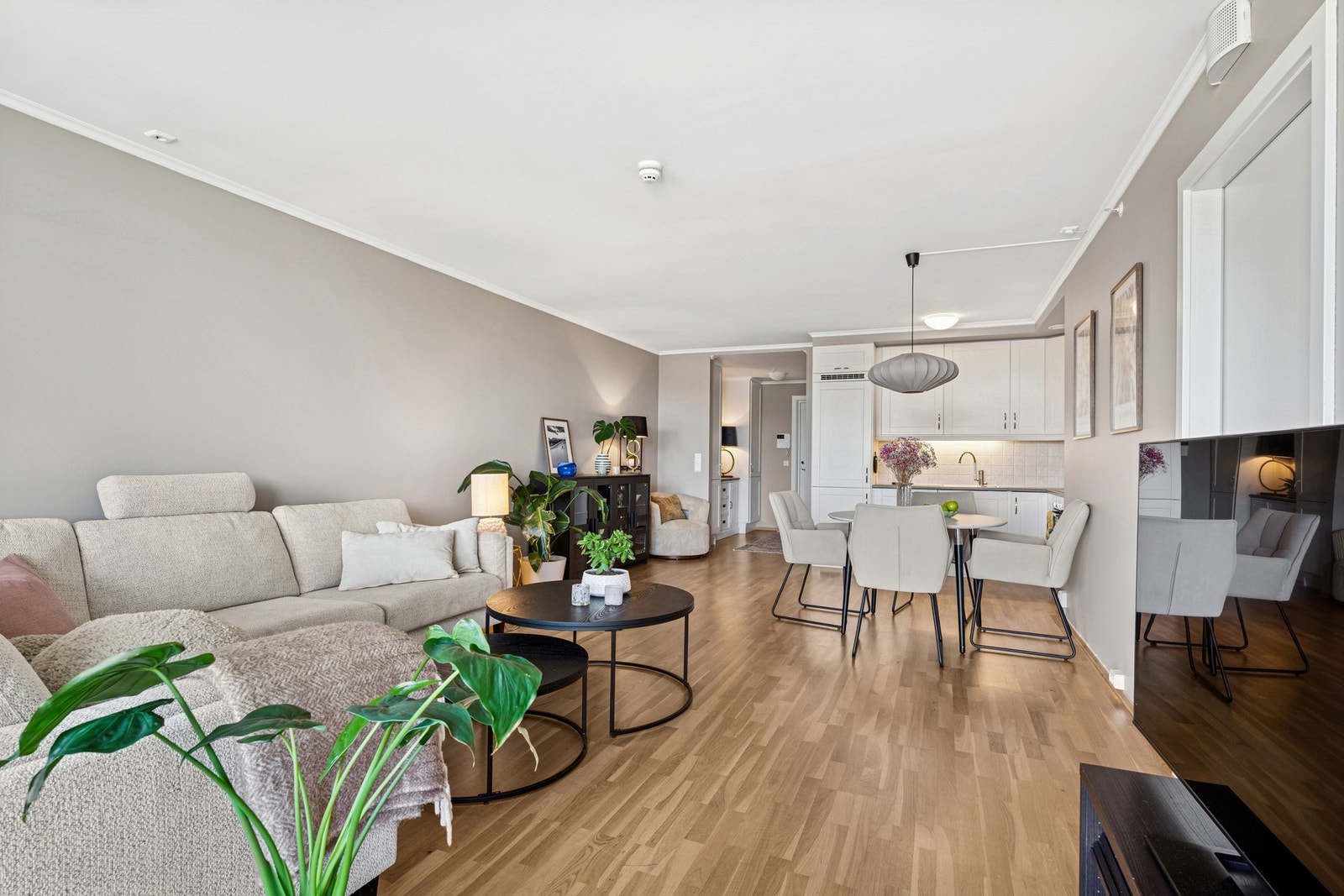 Romslig oppholdsrom med åpen løsning mellom stue og spisestue Galleribilde