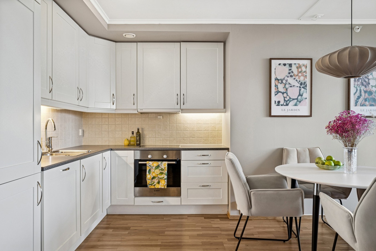 Pent kjøkken med integrerte hvitevarer, overskap i klassisk stil og godt med benkeplass. Galleribilde